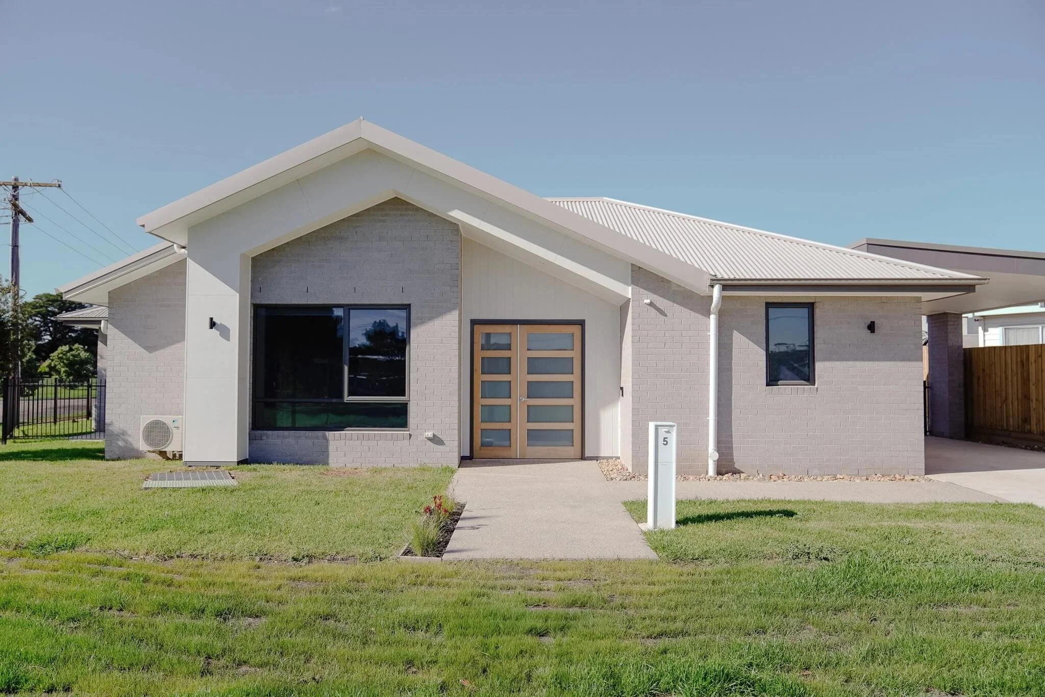Modern single-story house with a gable roof and brick exterior.