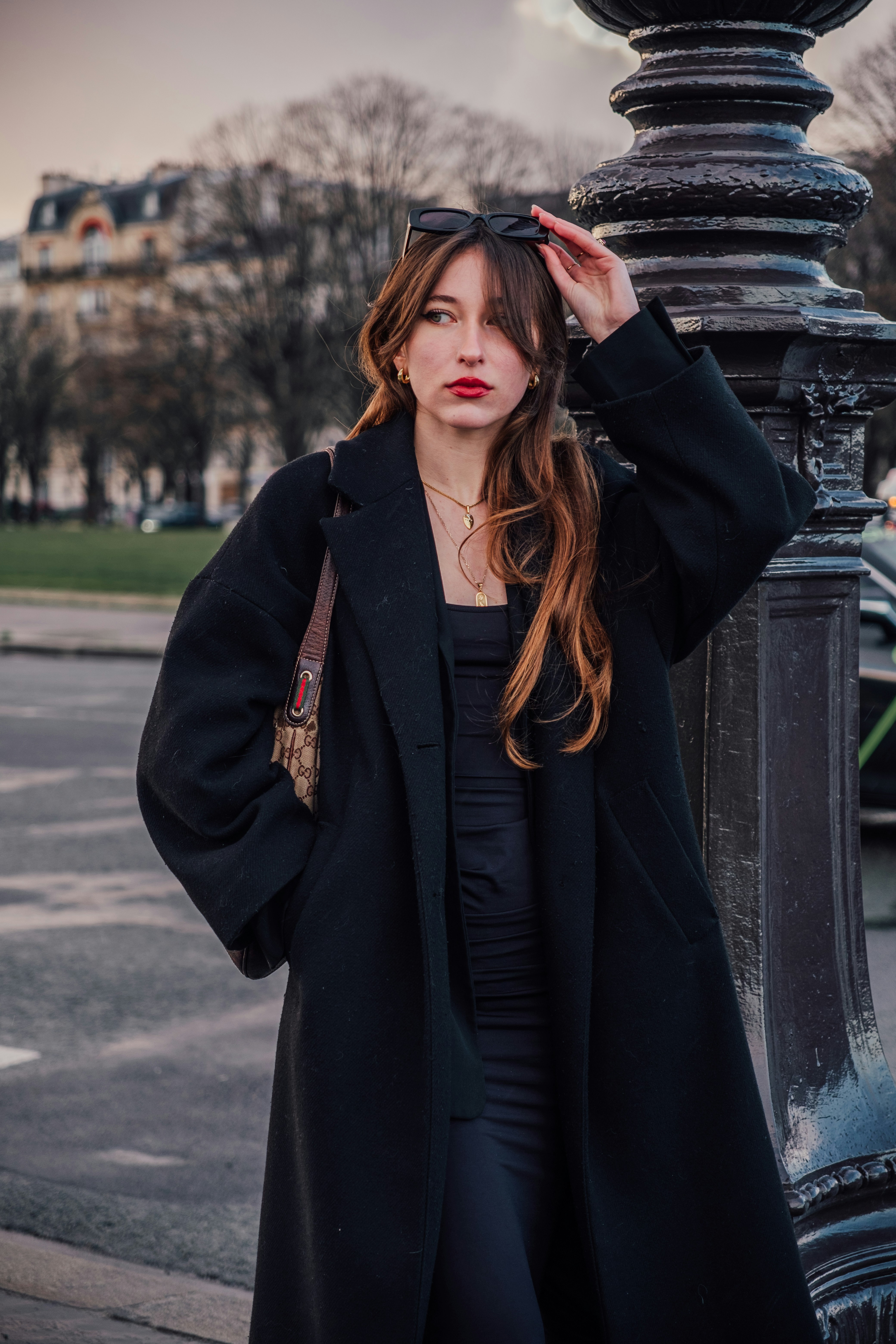 a woman leaning against a pole with her hand on her head