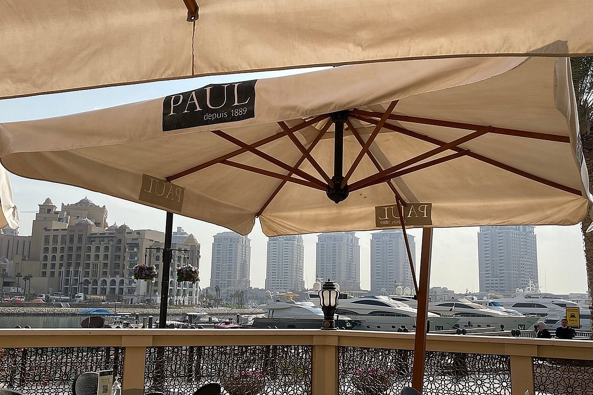 La terrasse de Paul à Porto Arabia, sur The Pearl, sous les parasols au nom de la boulangerie, face à la marina et aux tours du quartier