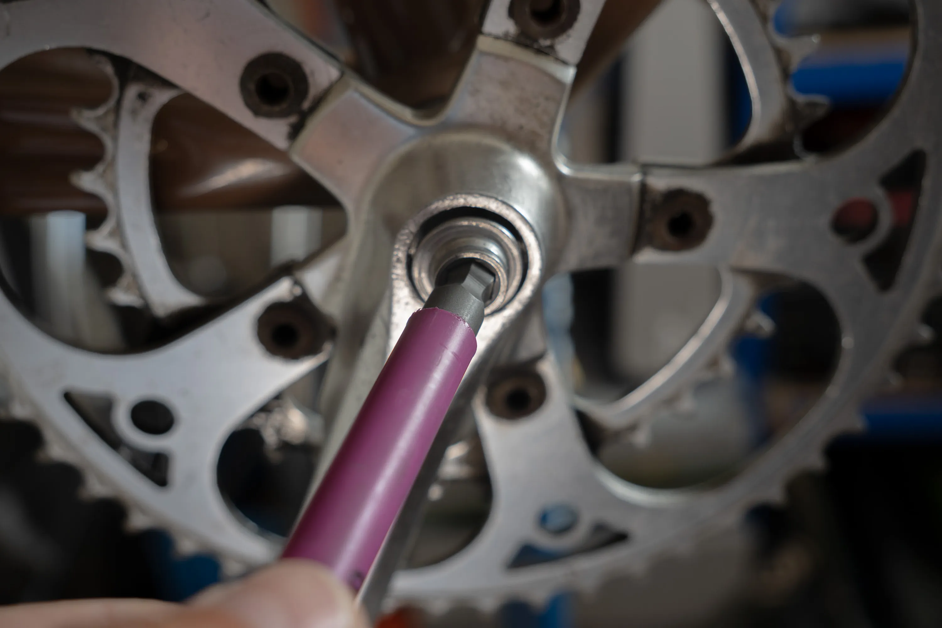 A close up of a person working on a bike crankset