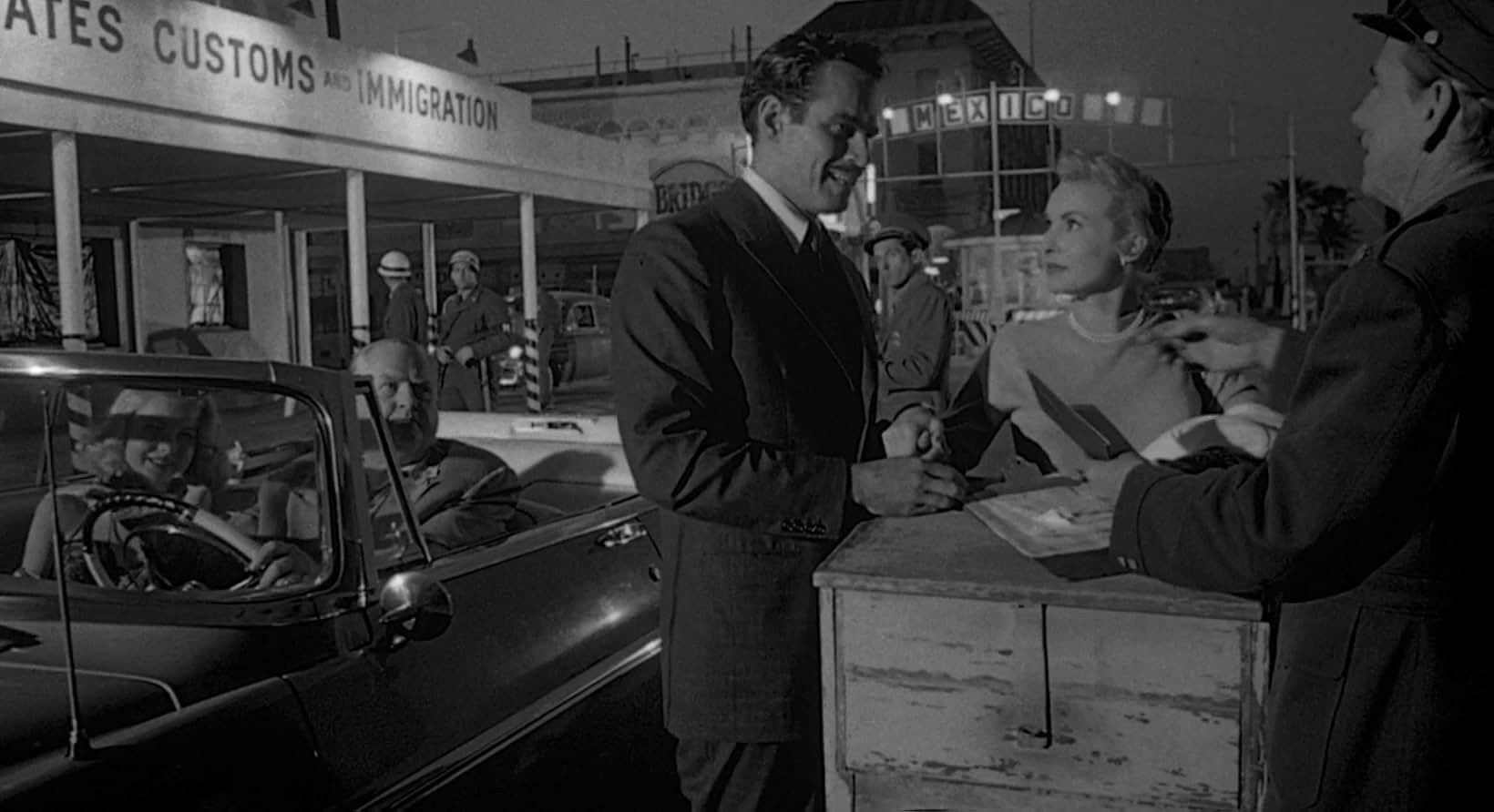 A black-and-white image of people at a counter in a diner, engaged in conversation.
