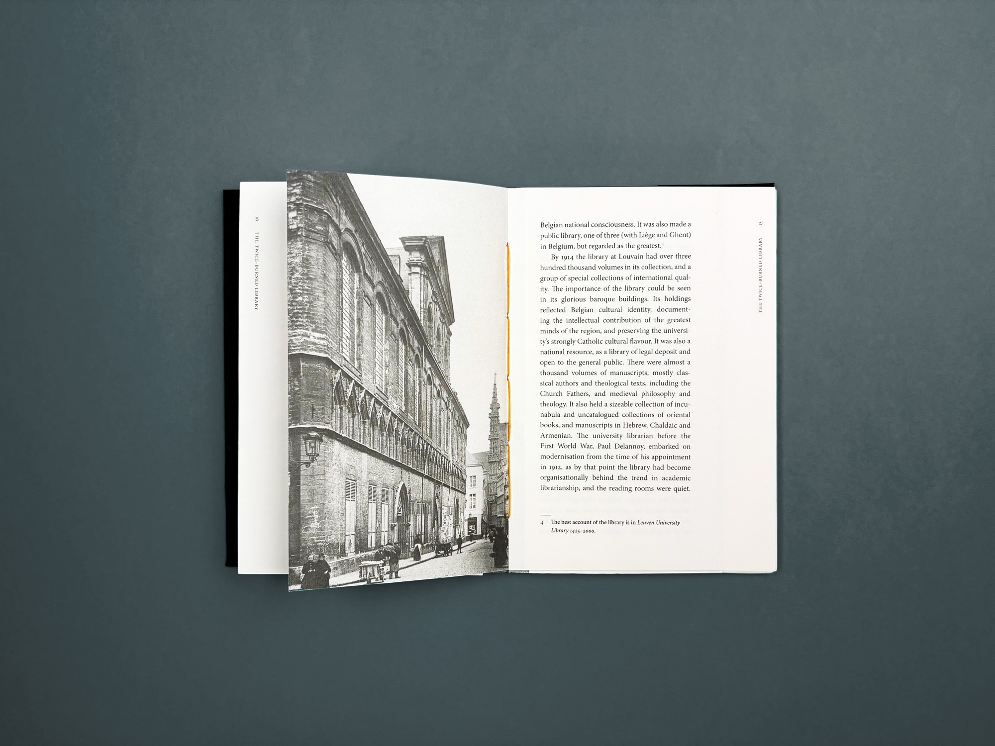 Een bovenaanzicht van een openliggend boek tegen een grijze achtergrond. De linkerpagina toont een zwart-wit foto van een historisch gebouw, de rechterpagina bevat strakke kolommen tekst met ruime marges.
