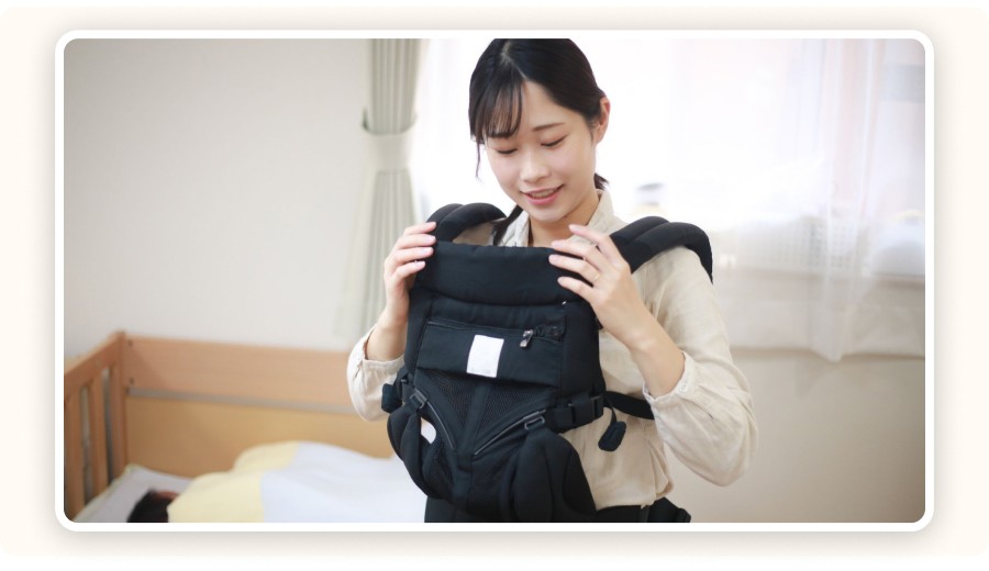Young mom adjusting an ergonomic baby carrier
