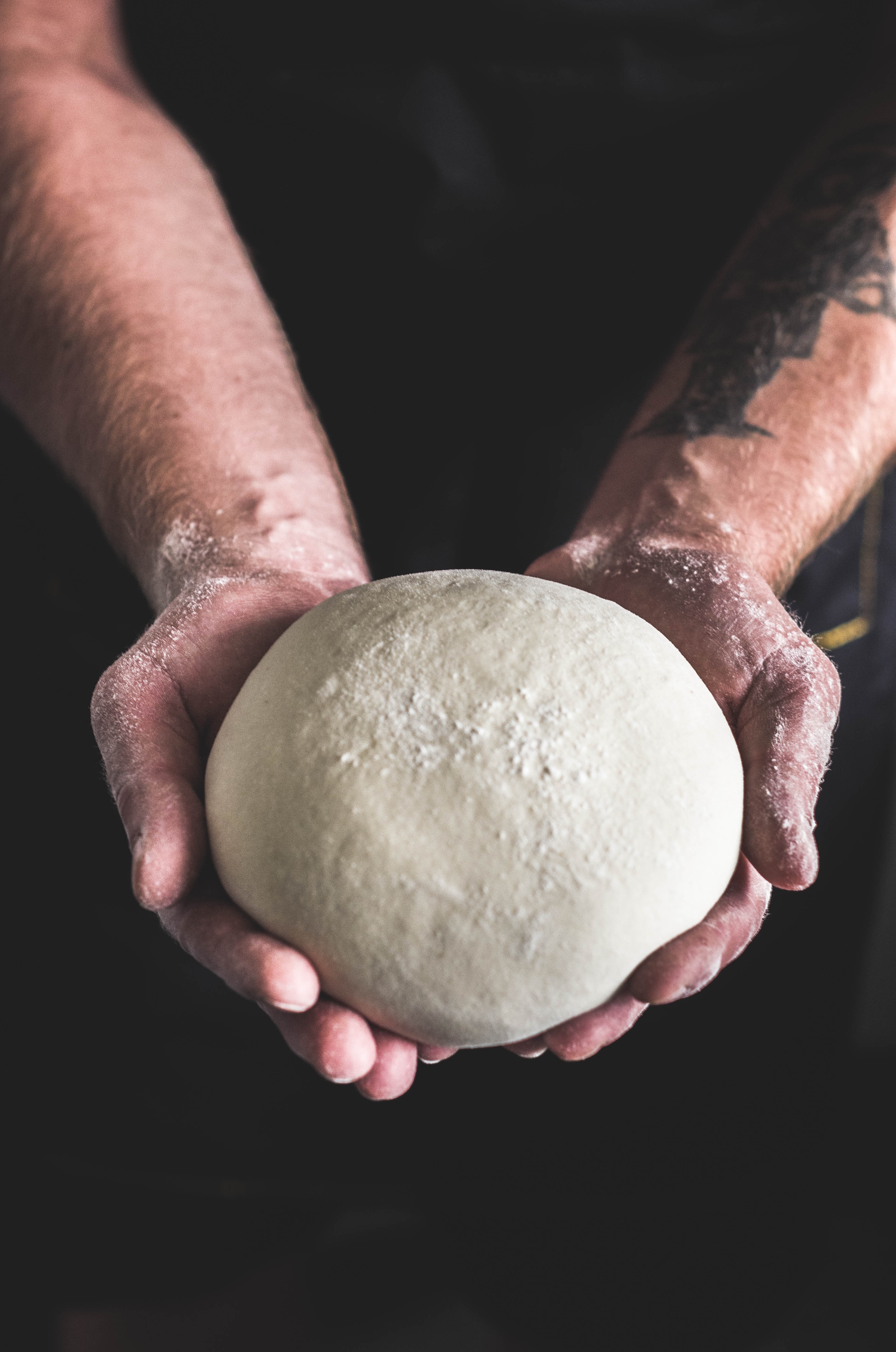 Koch bei Pizza & Pasta formt geschickt Pizzateig mit den Händen, demonstriert handwerkliche Kunst der Pizzaherstellung.