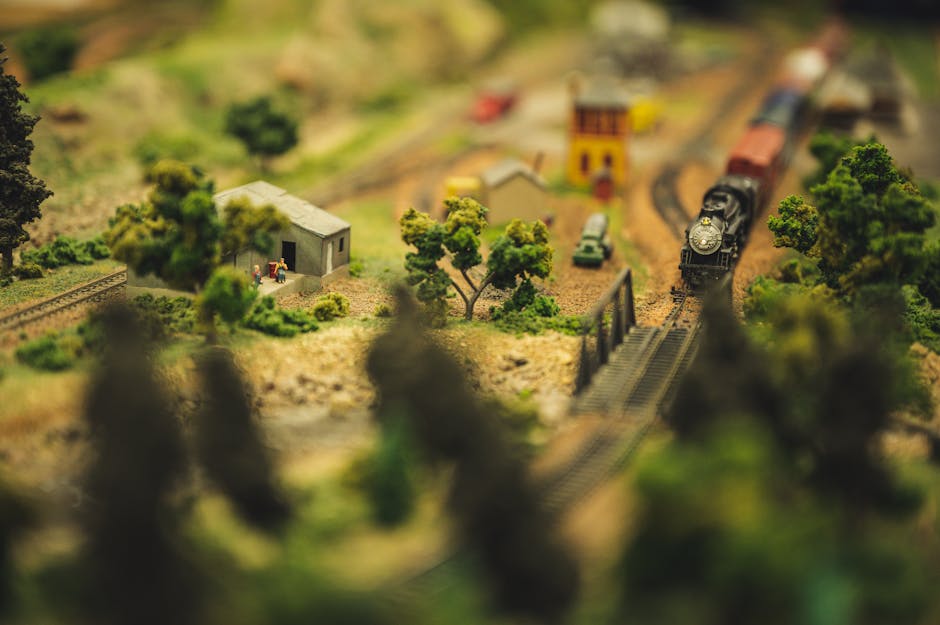 A detailed model train diorama showcasing a miniature landscape with tracks, buildings, and trees.