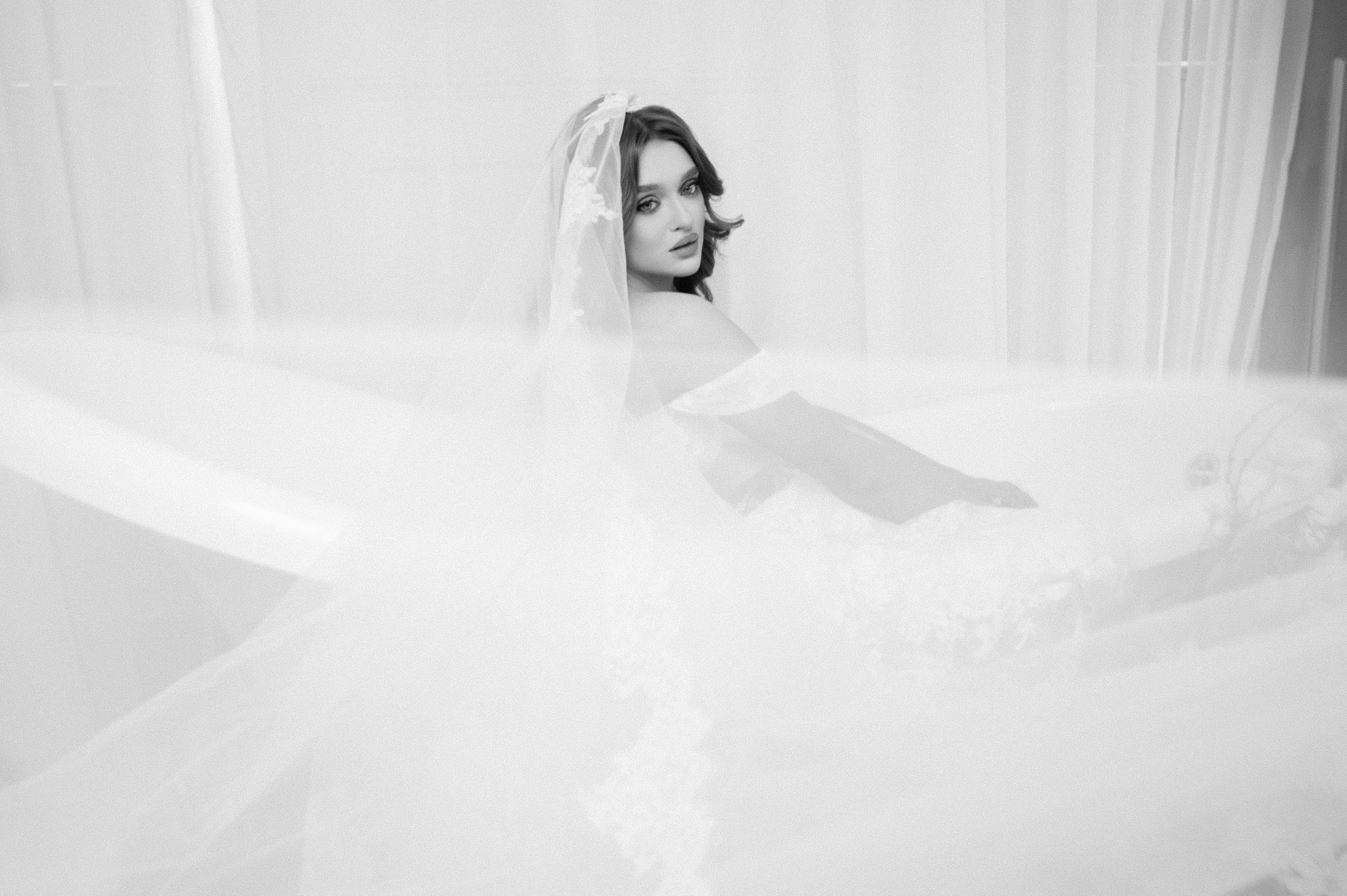 Mireasă fotografiată prin voal într-un decor minimalist și luminos, fotografie de nuntă în București