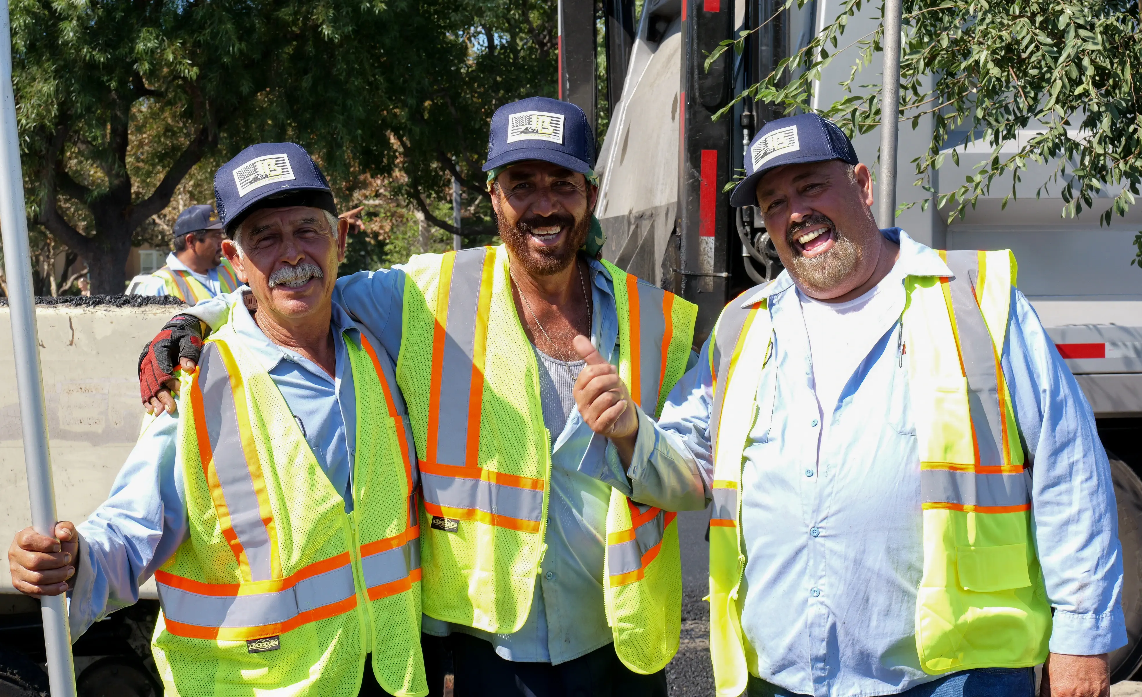 Three construction workers joking together on job site