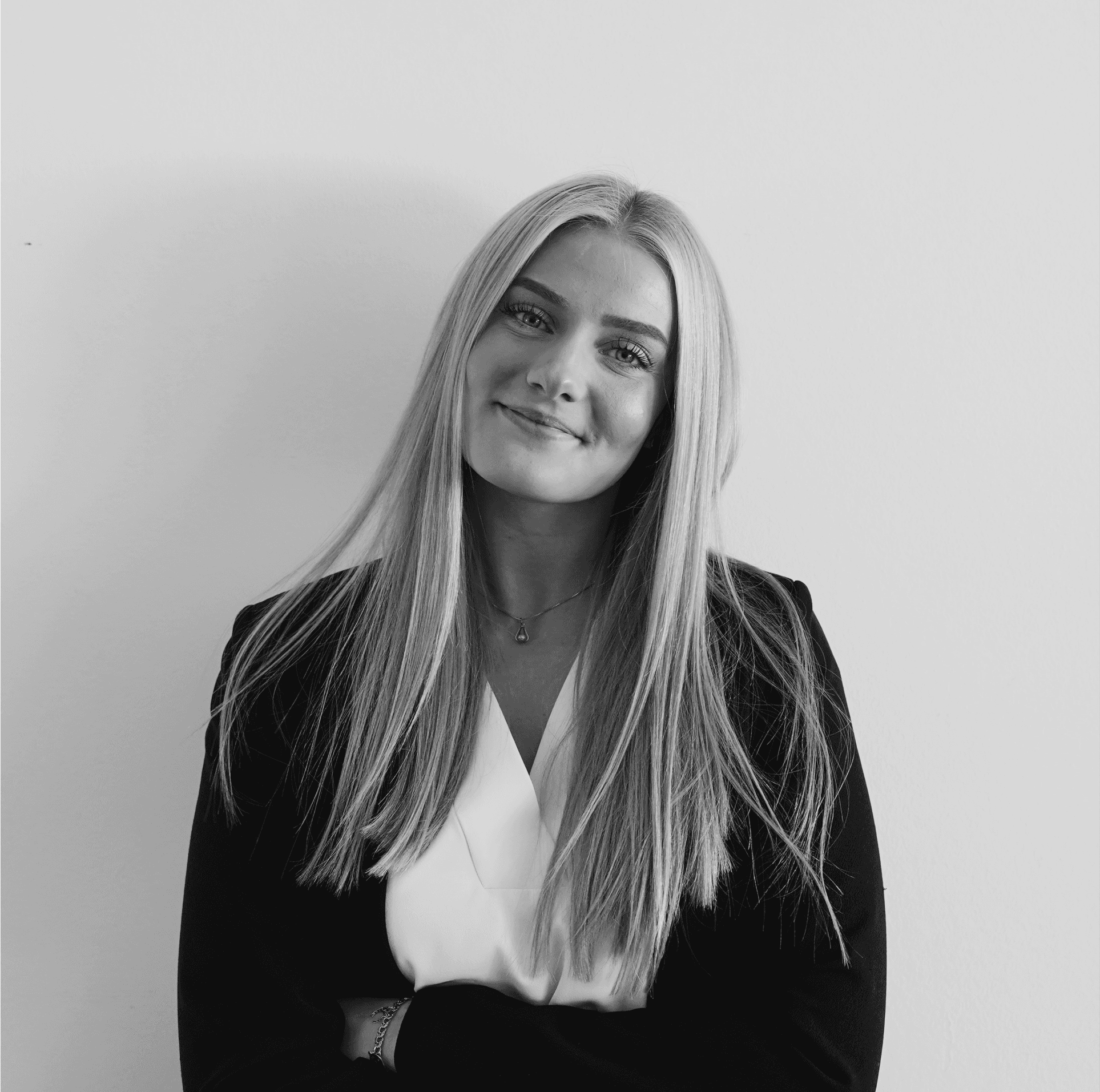 A monochrome image of a me smiling, confidently posing with arms crossed against a wall and making direct eye contact with the camera.