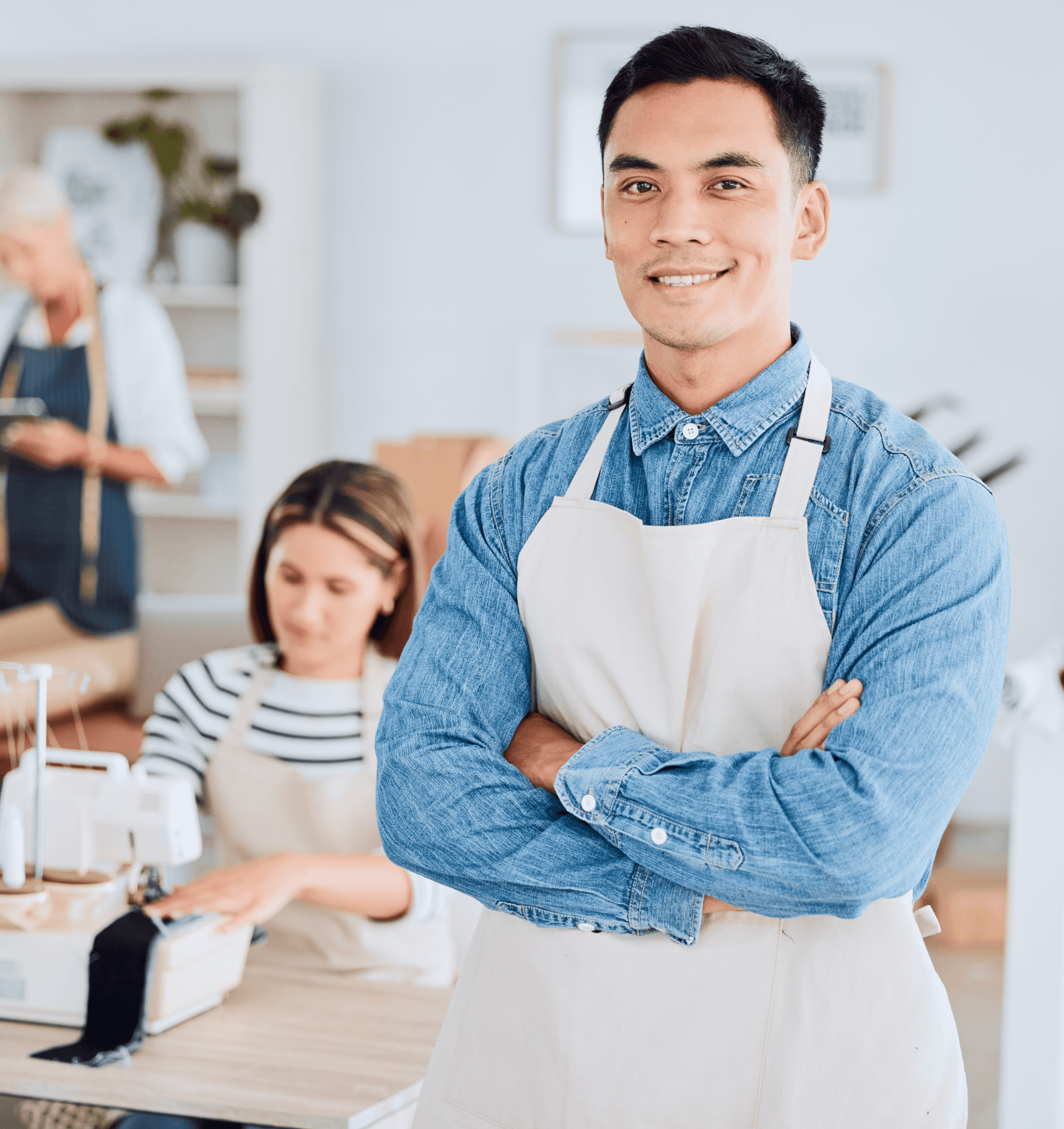 Male Entrepreneur with a blue shirt and a white overall and a team working in the back