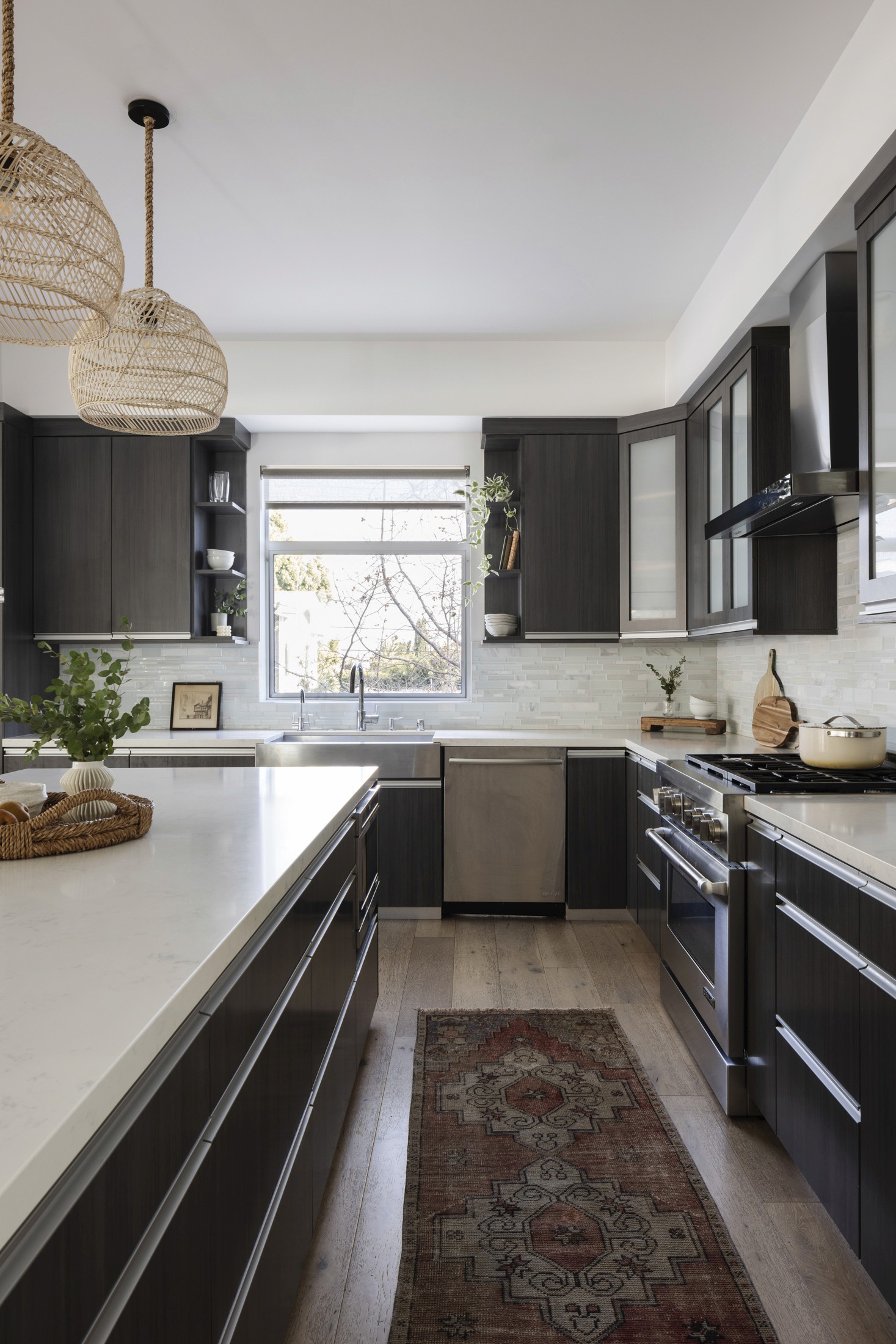 Large open concept kitchen with island, counter stools, pendant lighting above island, and dark cabinetry in l-shape