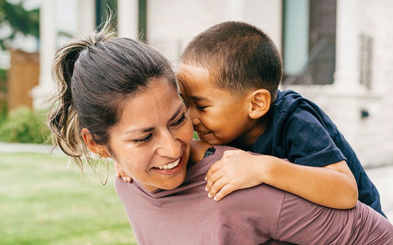 40 year old Hispanic woman givng a piggy back ride to her son