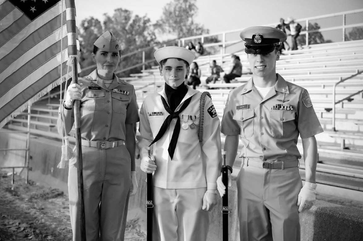 Three US military members at the Rodeo holding American flag