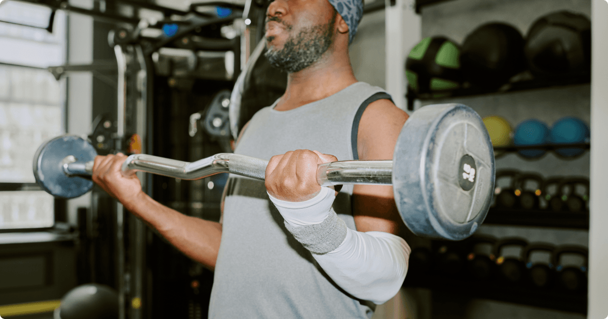 A man performing a bicep curl using an EZ curl bar in the gym