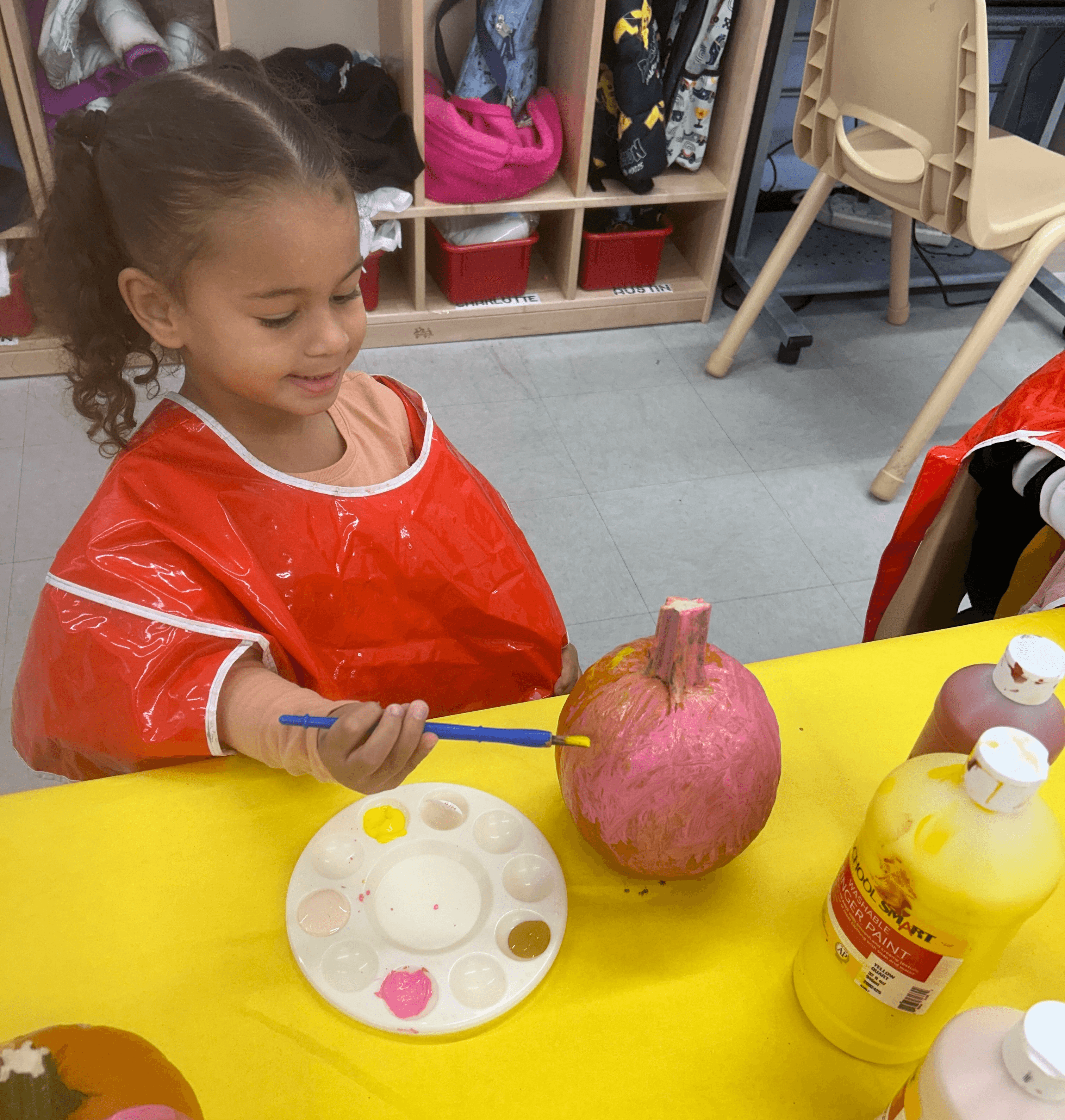 A young participant paints her pumpkin pink.