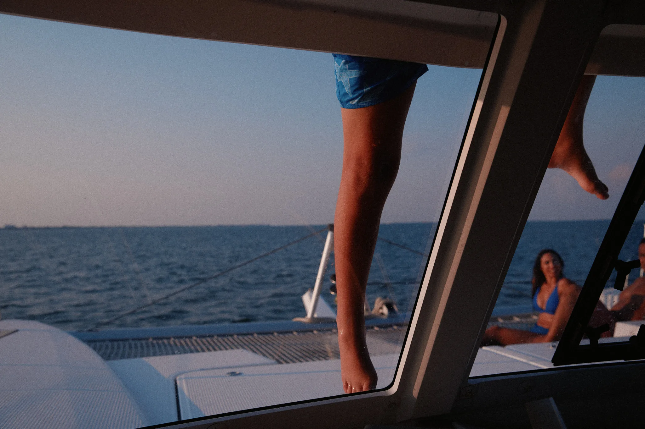 bare leg on catamaran window ledge — lifestyle photography by Tom Kubik