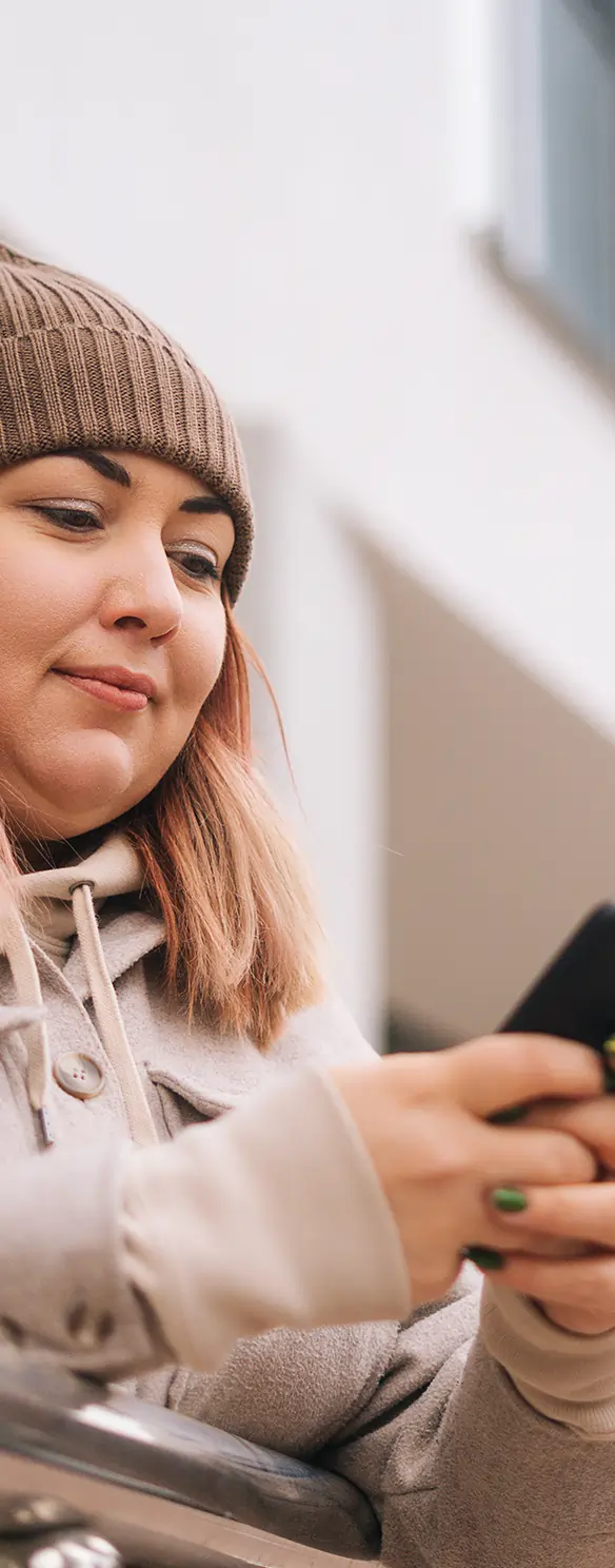 Woman outdoors texting while wearing winter attire.