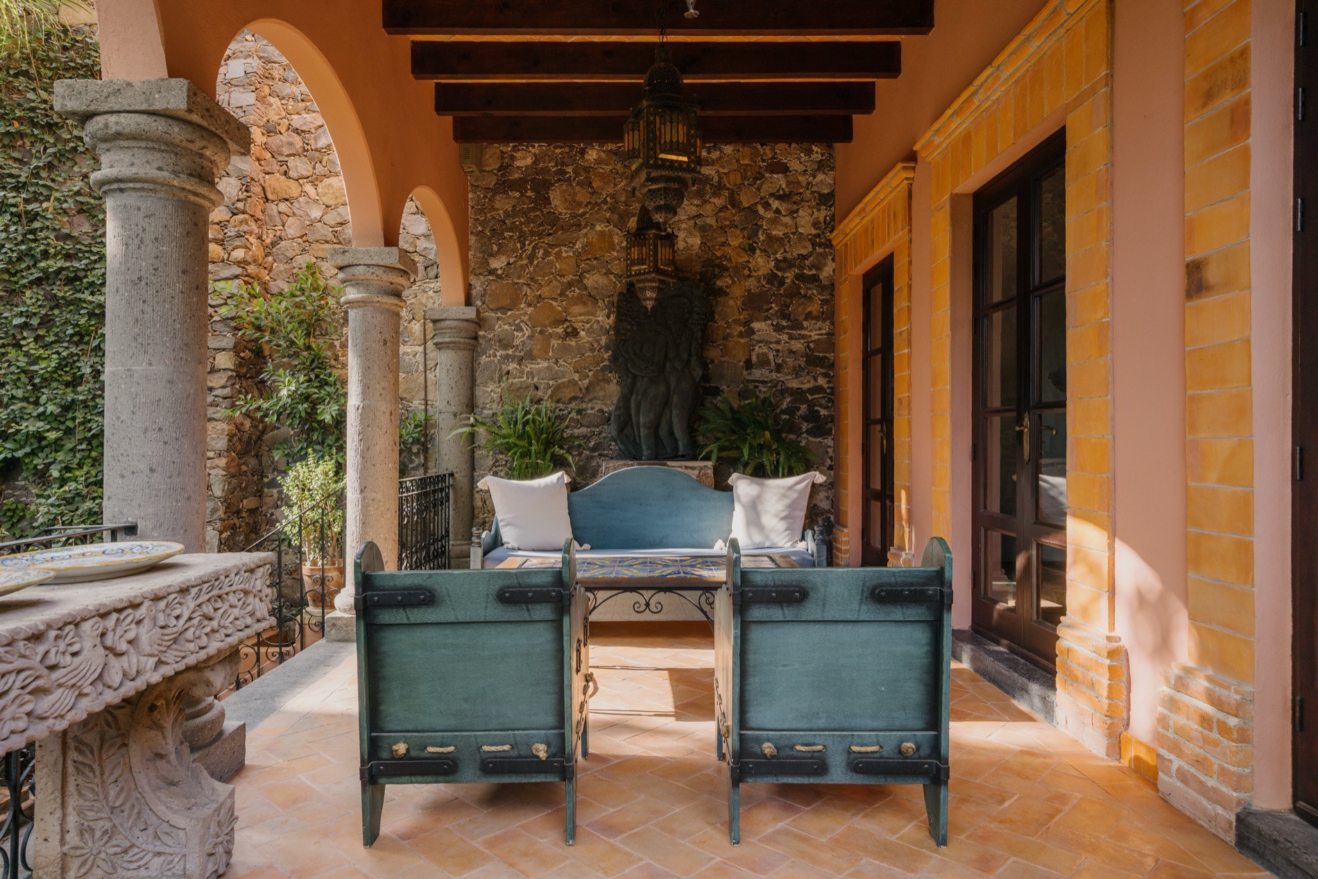 La Residencia San Miguel living room at evening with warm lighting, stone arches, and mezzanine balcony
