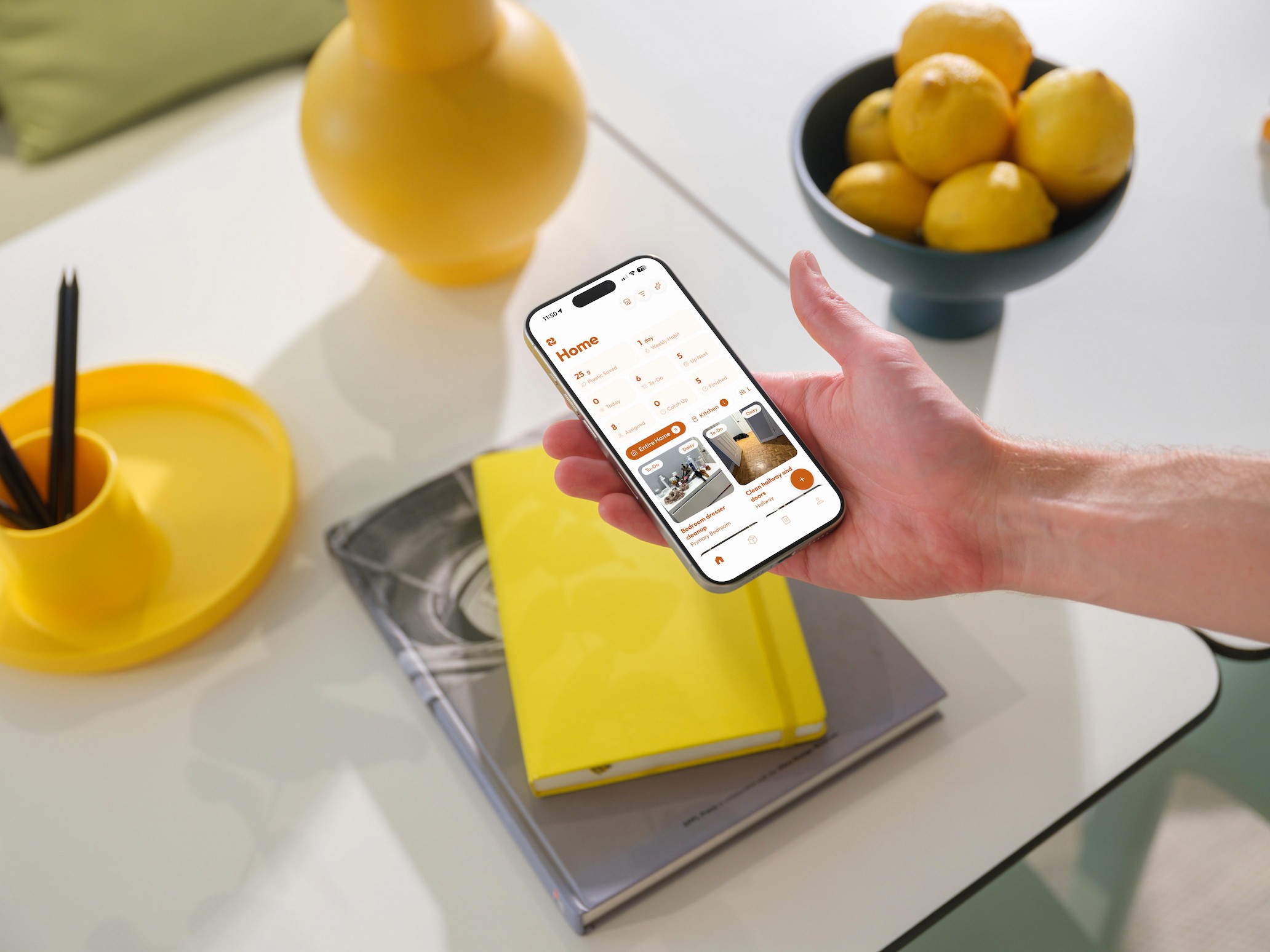 Hand holding a phone with a chore app open in a clean, tidy kitchen`