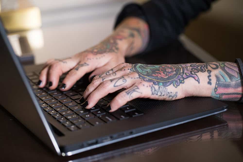 Person in a white off-shoulder top using a MacBook laptop, with text overlay 'What's new in digital?' and the fabrica® logo in the top corner.