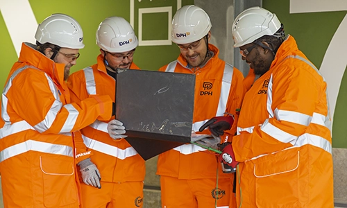 Modern glass building with illuminated interior and reflections at sunset