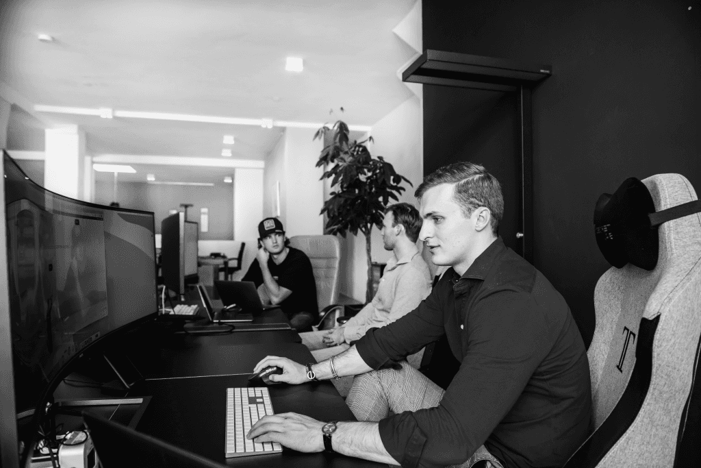 Three Flatline Agency team members working side by side at desks with large monitors