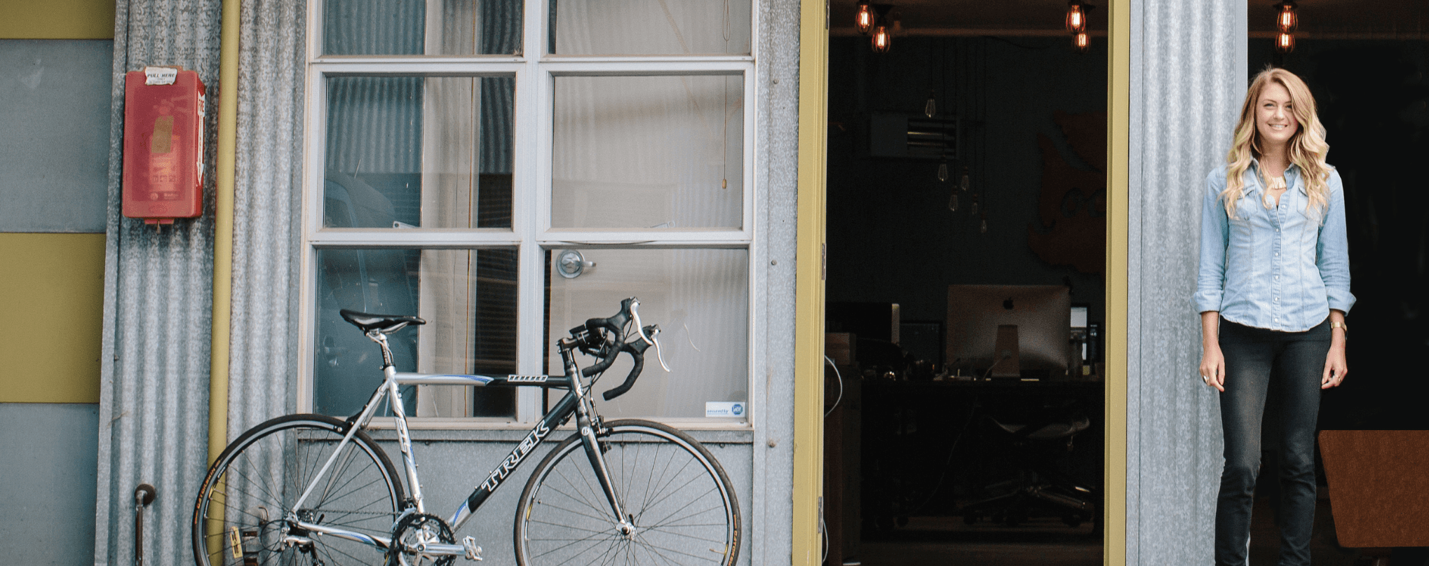 Portrait of blonde woman standing next to a bike