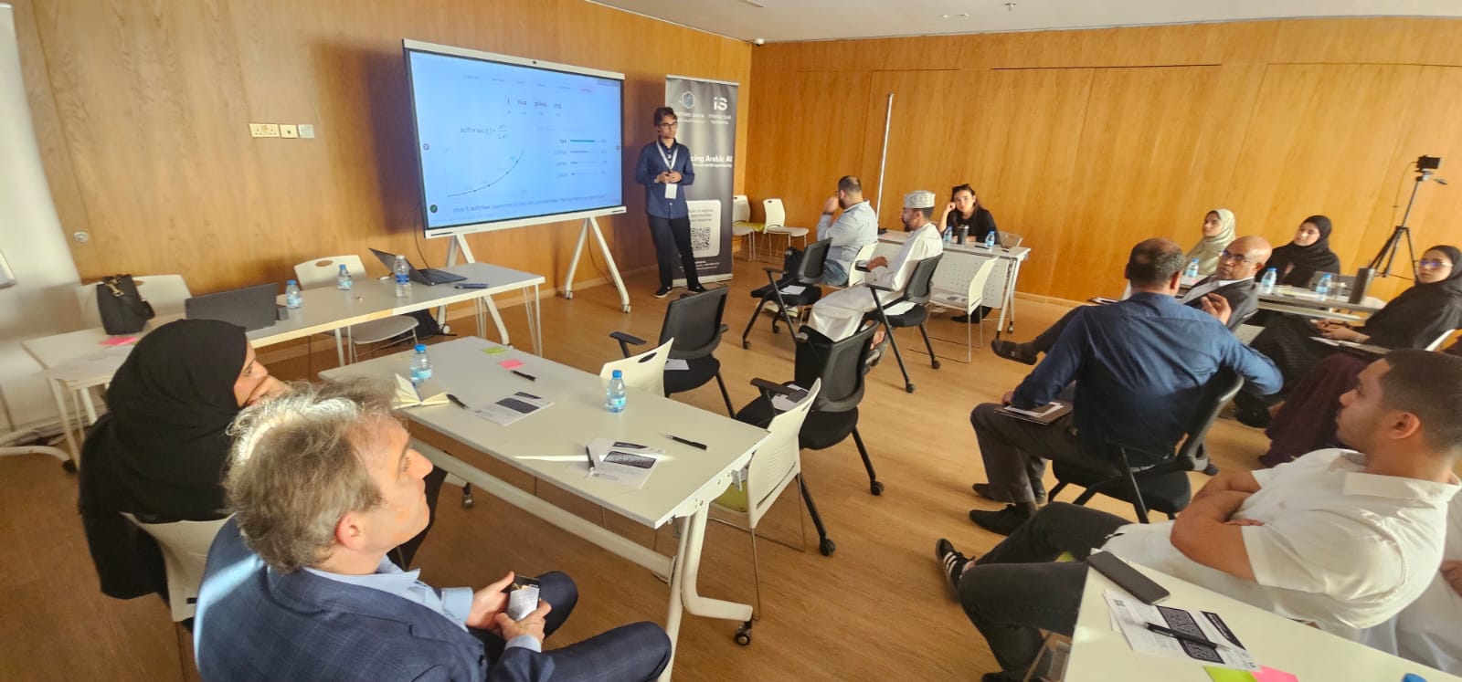 Future Data 'Why Does AI Struggle with Arabic?' workshop — presenter explaining how language models work to an attentive audience in Muscat.