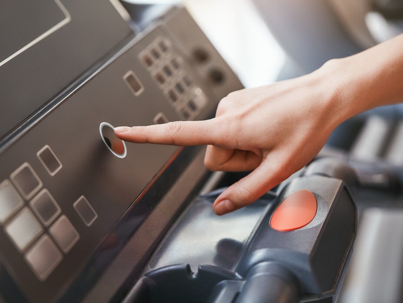 woman setting treadmill incline for weight loss and pressing start at the gym to begin her workout