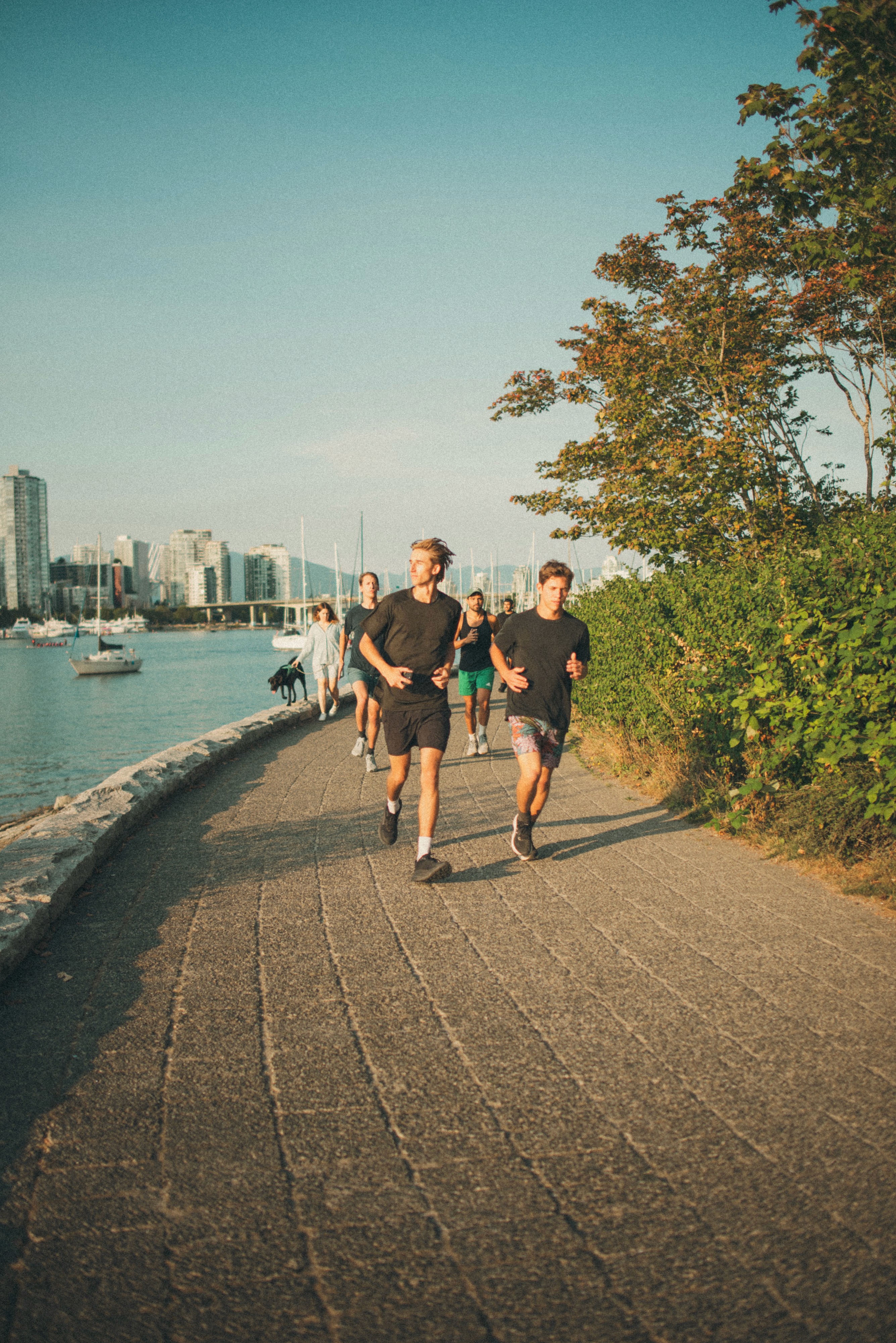 Two athletes wearing light gray sports tanks and sunglasses, standing side by side with their backs facing the camera against a dark sky.