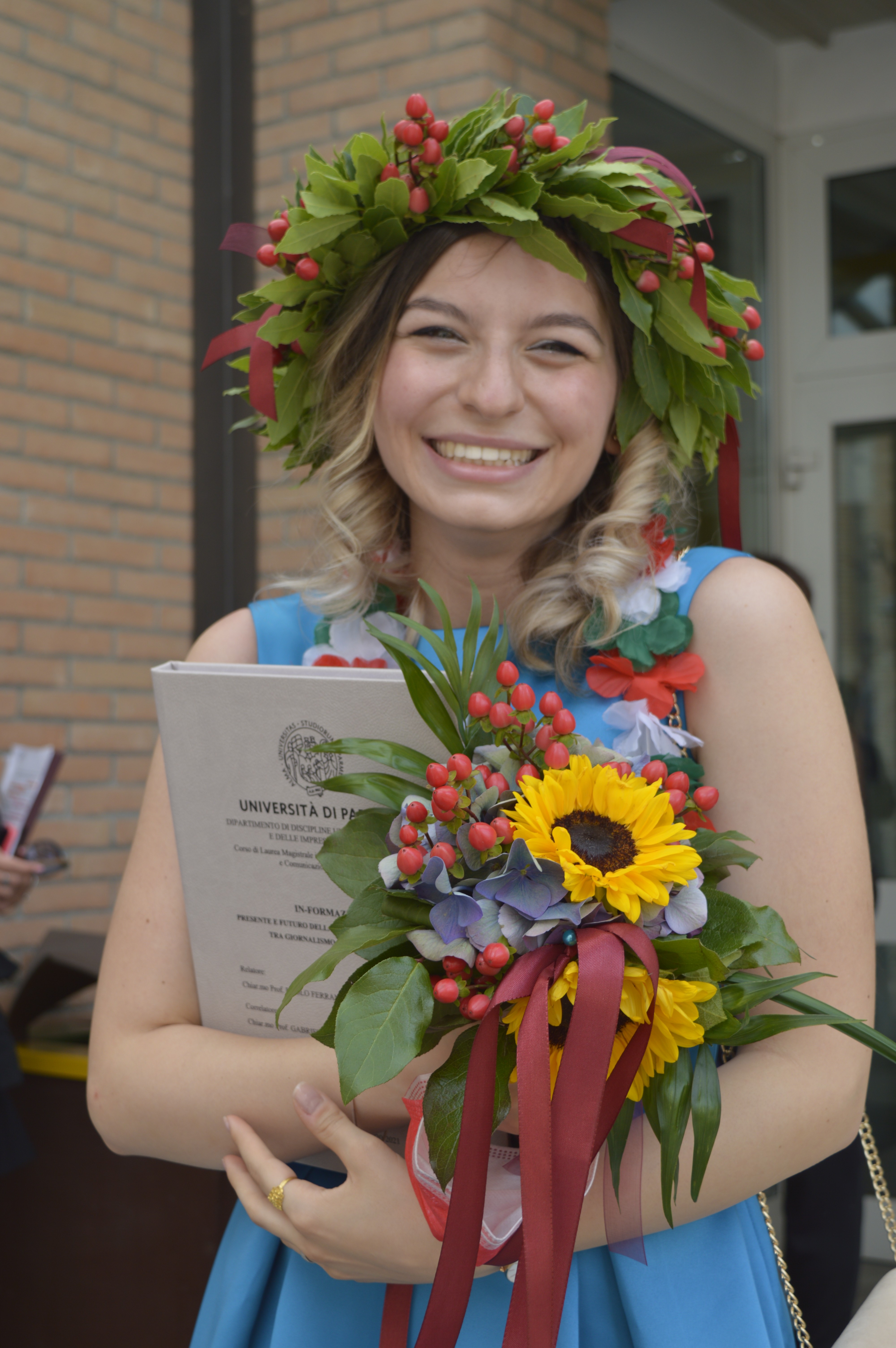 Silvia Vazzana con in testa una corona d'alloro e in mano la tesi di laurea magistrale e un bouquet di fiori