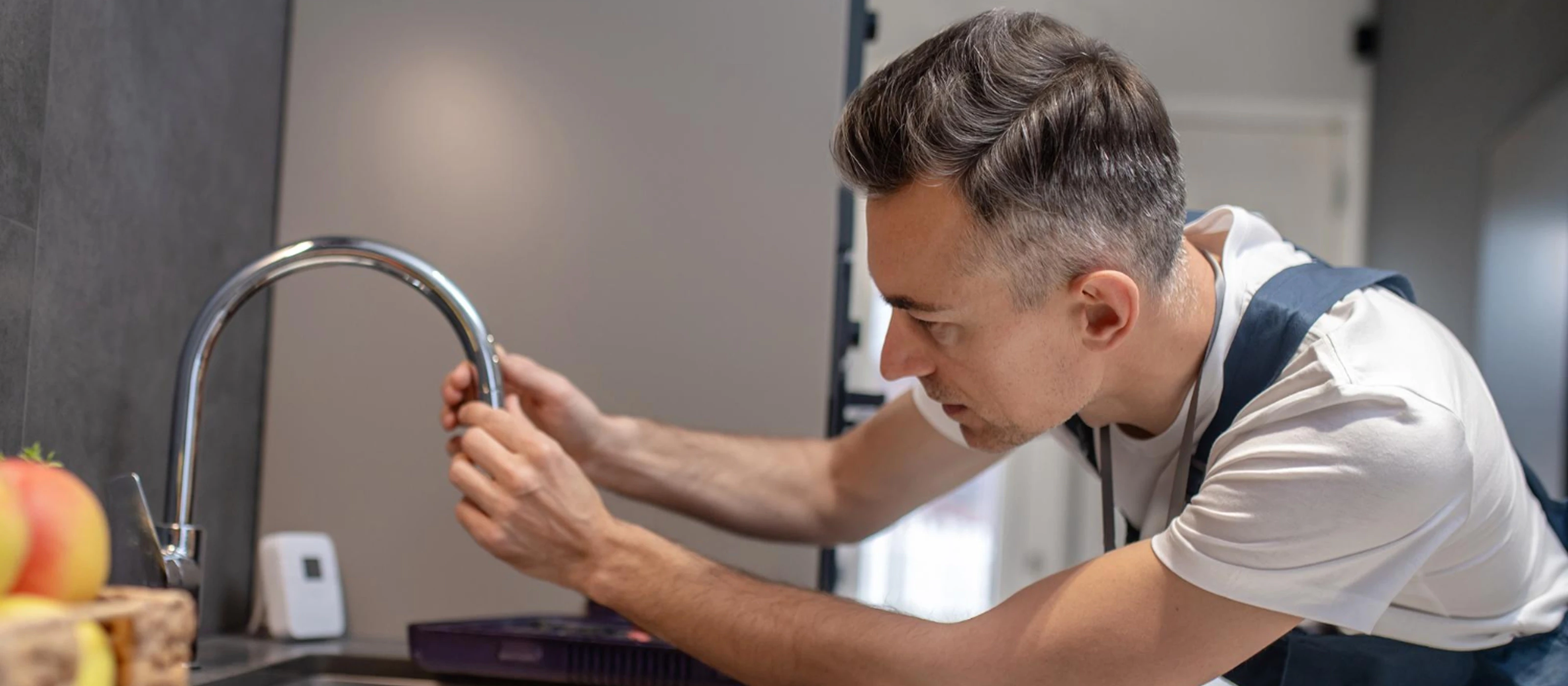 Plumber inspecting a kitchen faucet