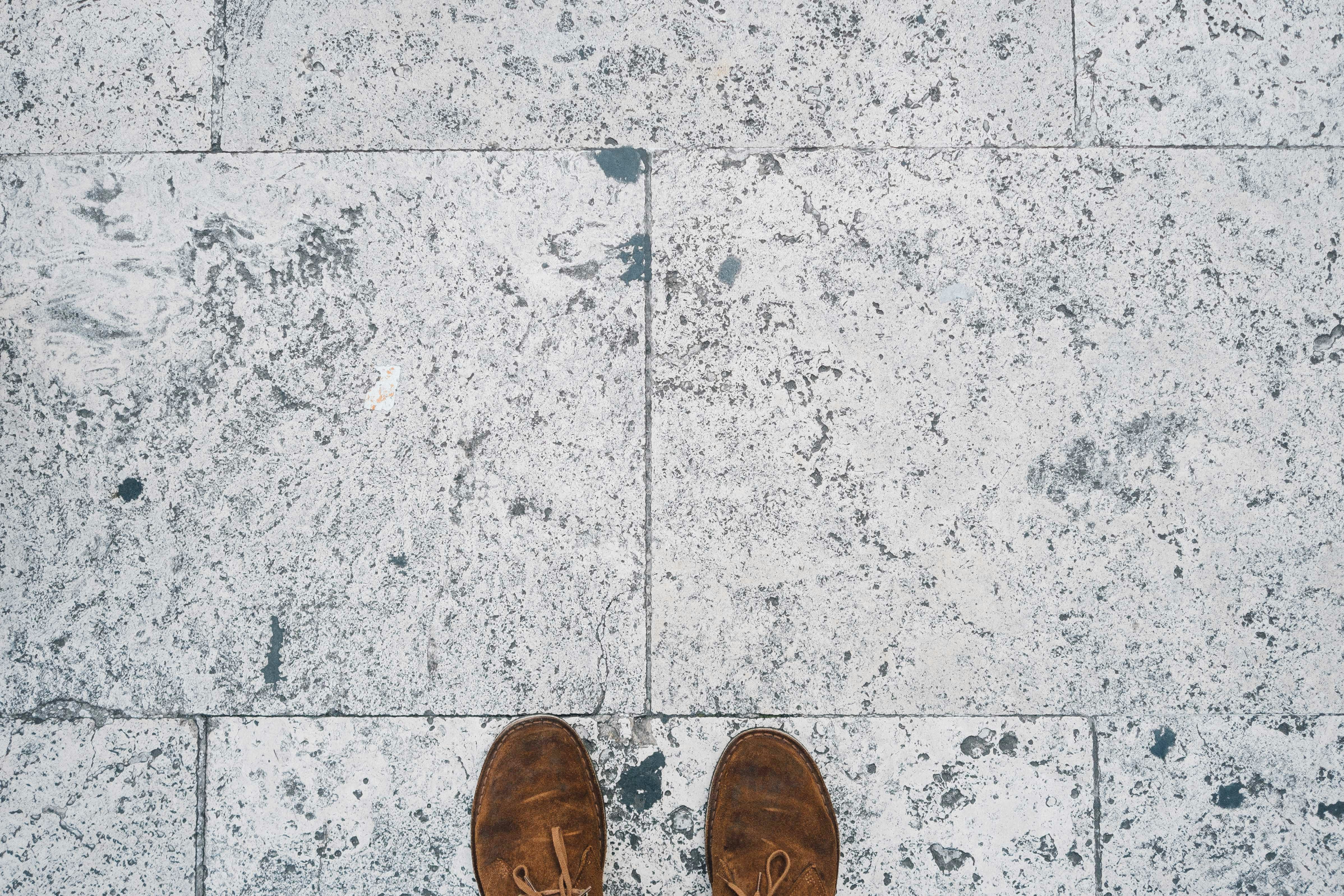 person in brown shoes standing on gray concrete floor