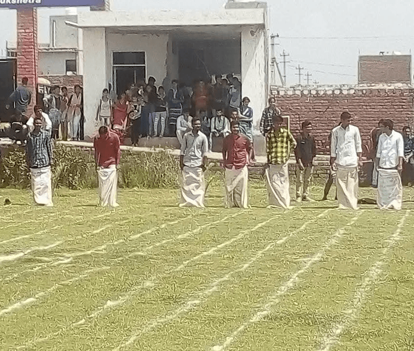 College students line up on a grassy field to participate in a fun sack race during a sports event.