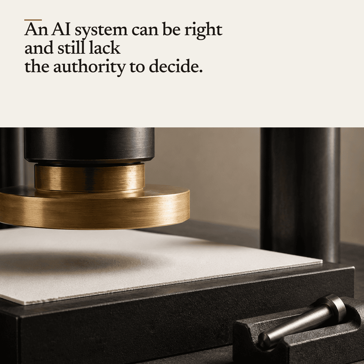 A heavy black-and-brass press hovers just above a blank sheet of card on a dark base; the die does not quite touch the paper.