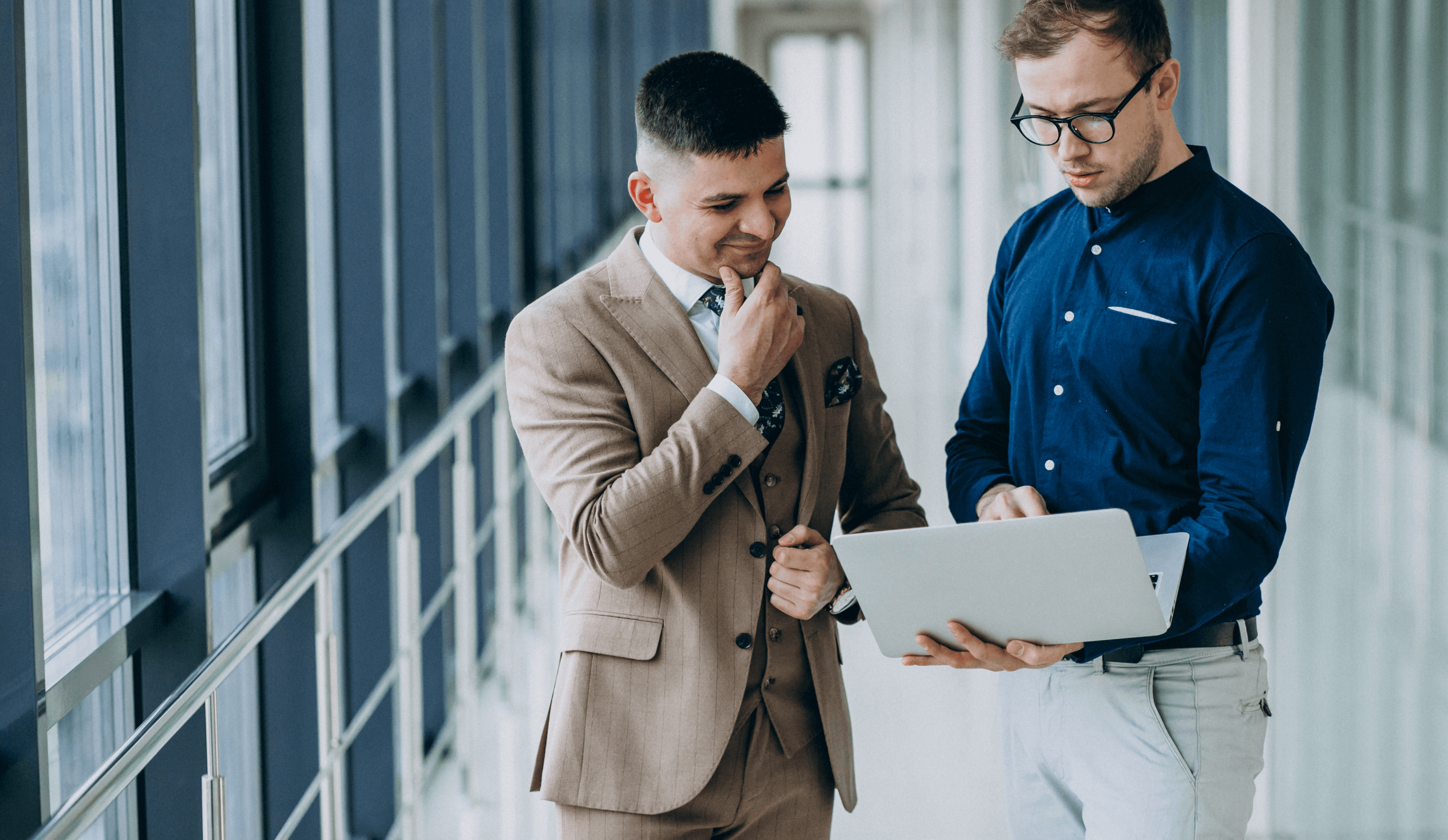 Two professional businessmen discussing work on a laptop in office.