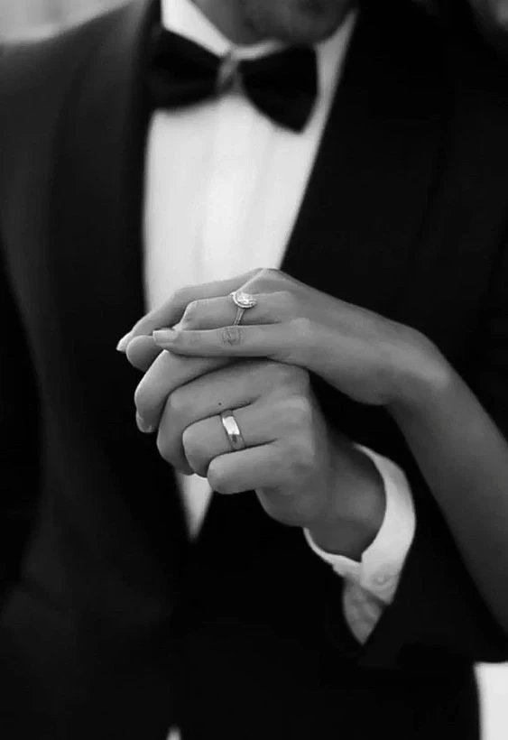 An artistic black-and-white shot of the bride and groom’s hands entwined, with their wedding rings subtly highlighted, a fine art capture by Out of The Blues Fine Art Wedding Photography in Hyderabad.