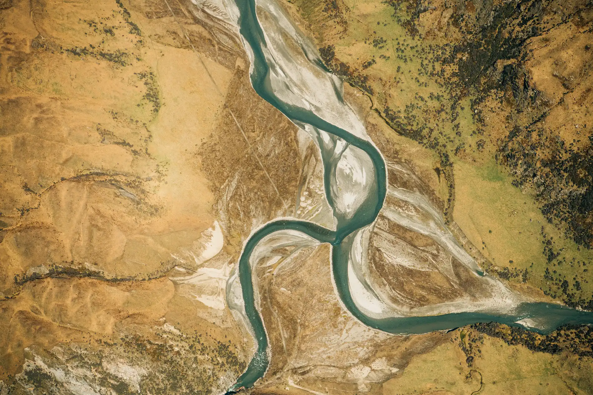 Aerial of a river meandering in wide loops across dry golden country