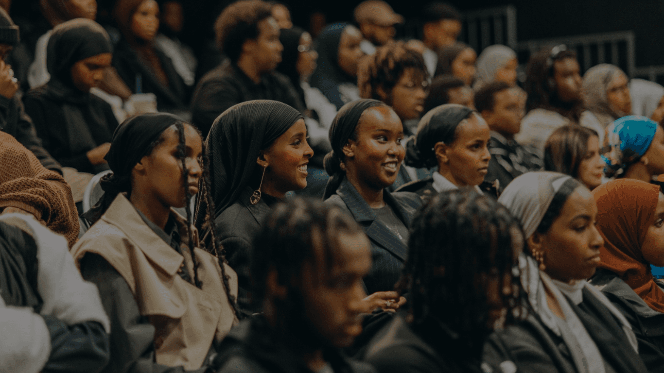 Members of the Somalis in Tech community seated in an audience at an event, smiling and looking towards the stage.