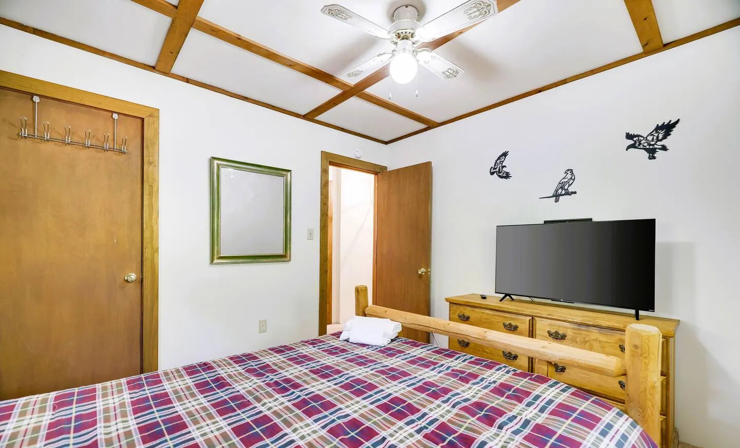 Upstairs full bedroom with plaid bedding, dresser and TV at RedHawk Chalet