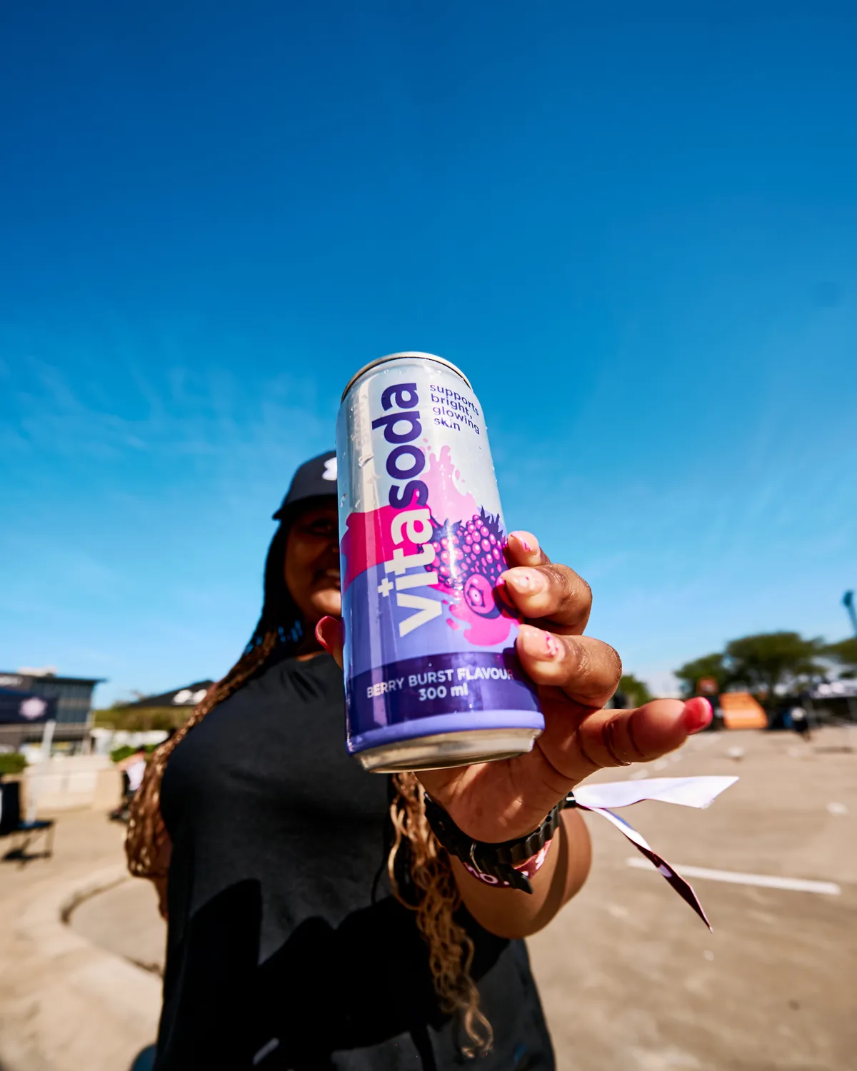Someone outdoors in the sun holding out a can of Vita Soda Glow