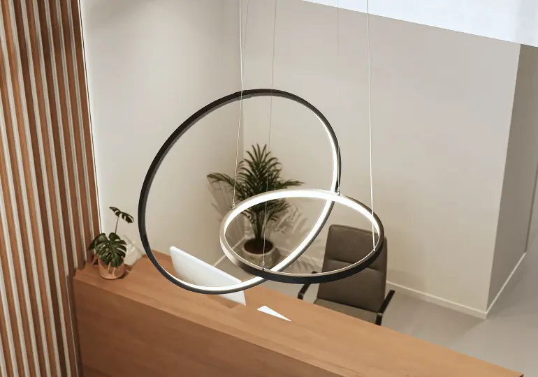 Lámpara LED circular colgante Beneito Faure iluminando recepción moderna con mostrador de madera