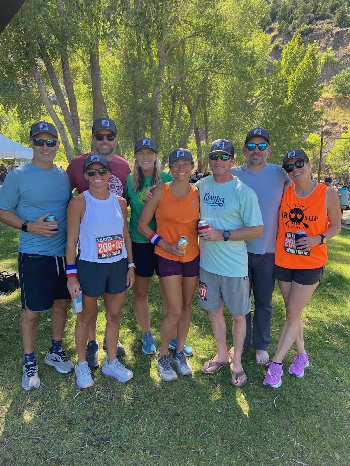Team standing arm in arm under the trees after the race