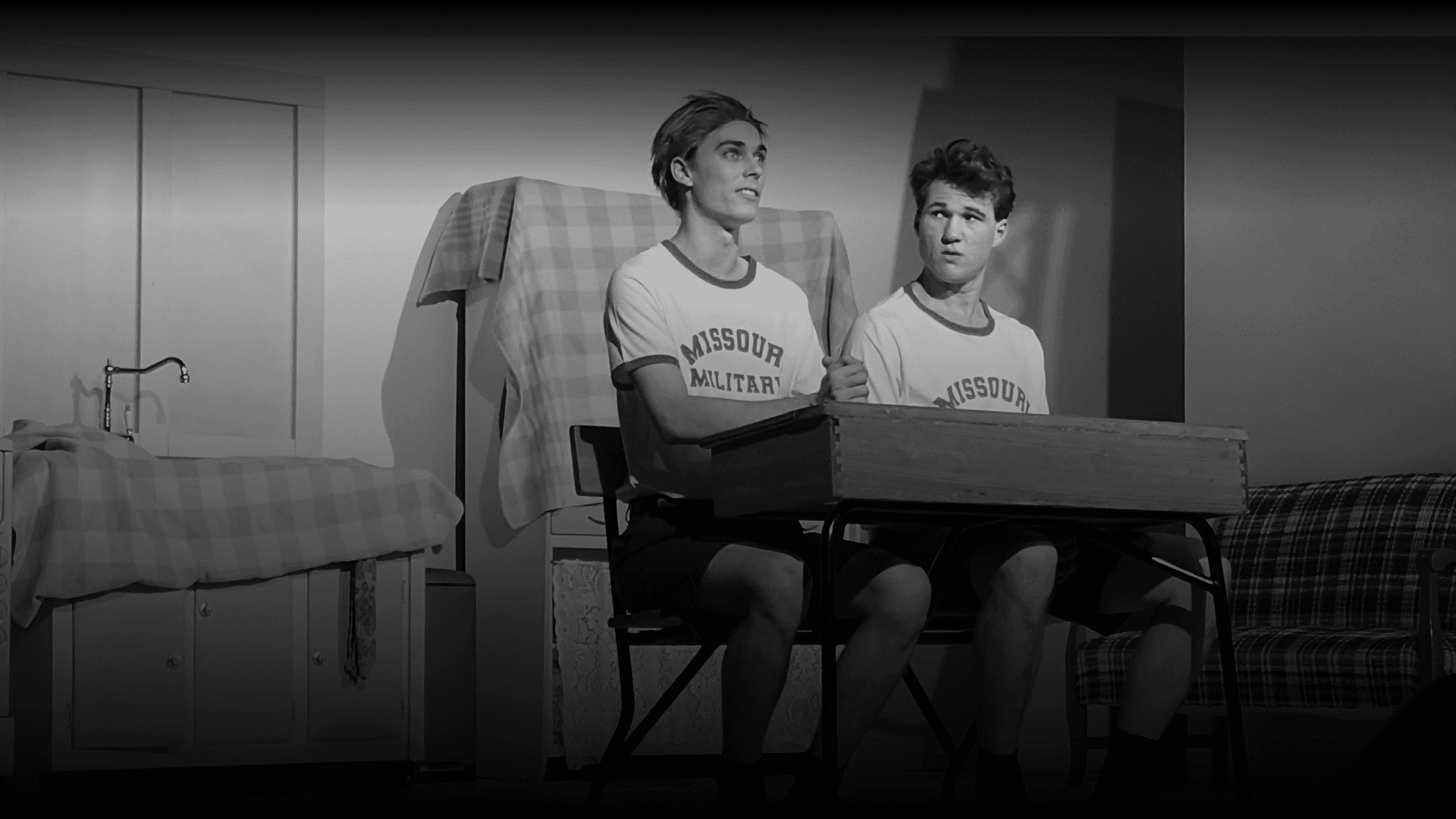 Two actors sitting side by side performing a play