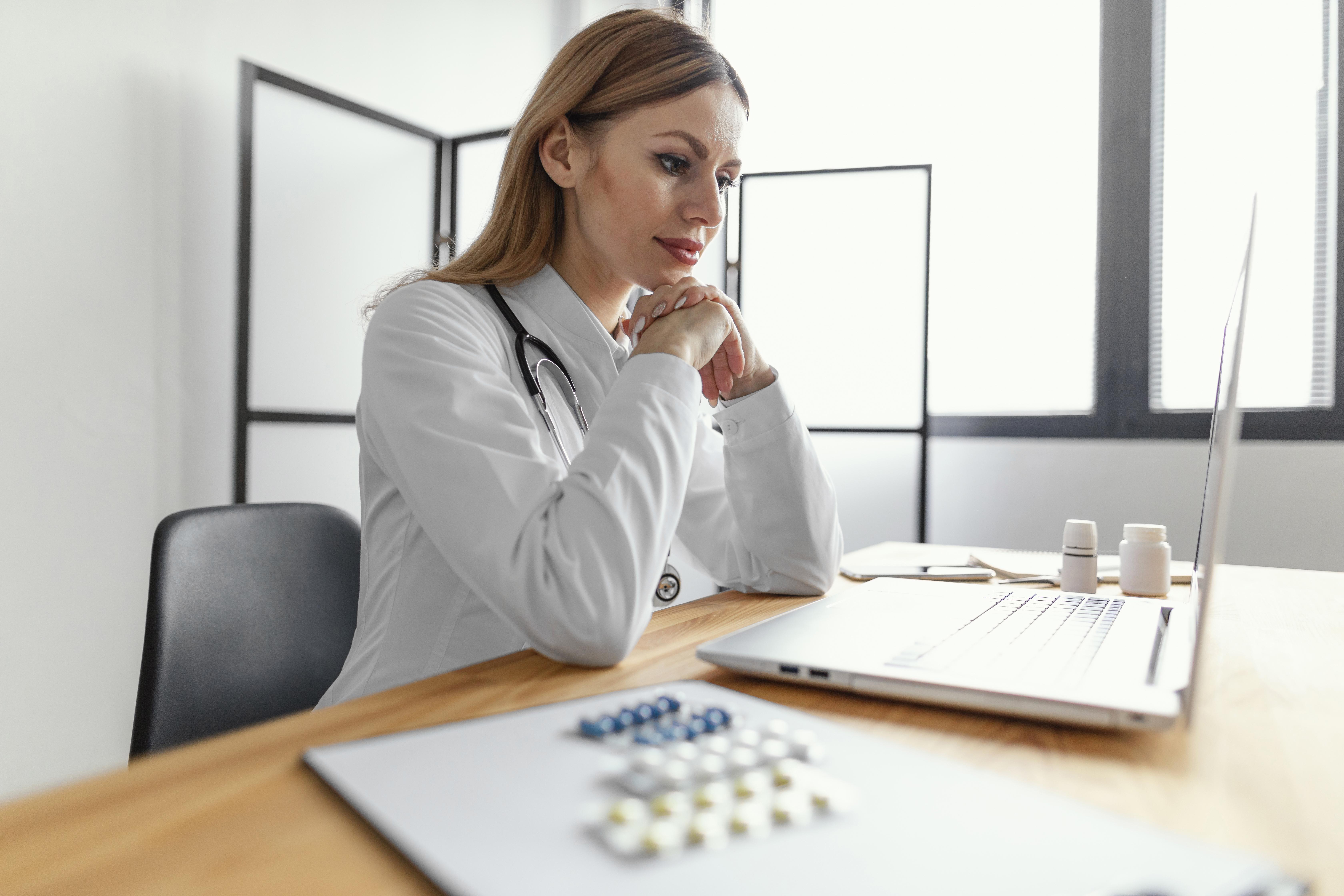 Psychiatrist reviewing patient medications on a laptop, representing how CompliantChatGPT assists with medication management by detecting drug interactions, generating structured psychiatric notes, and improving treatment safety.