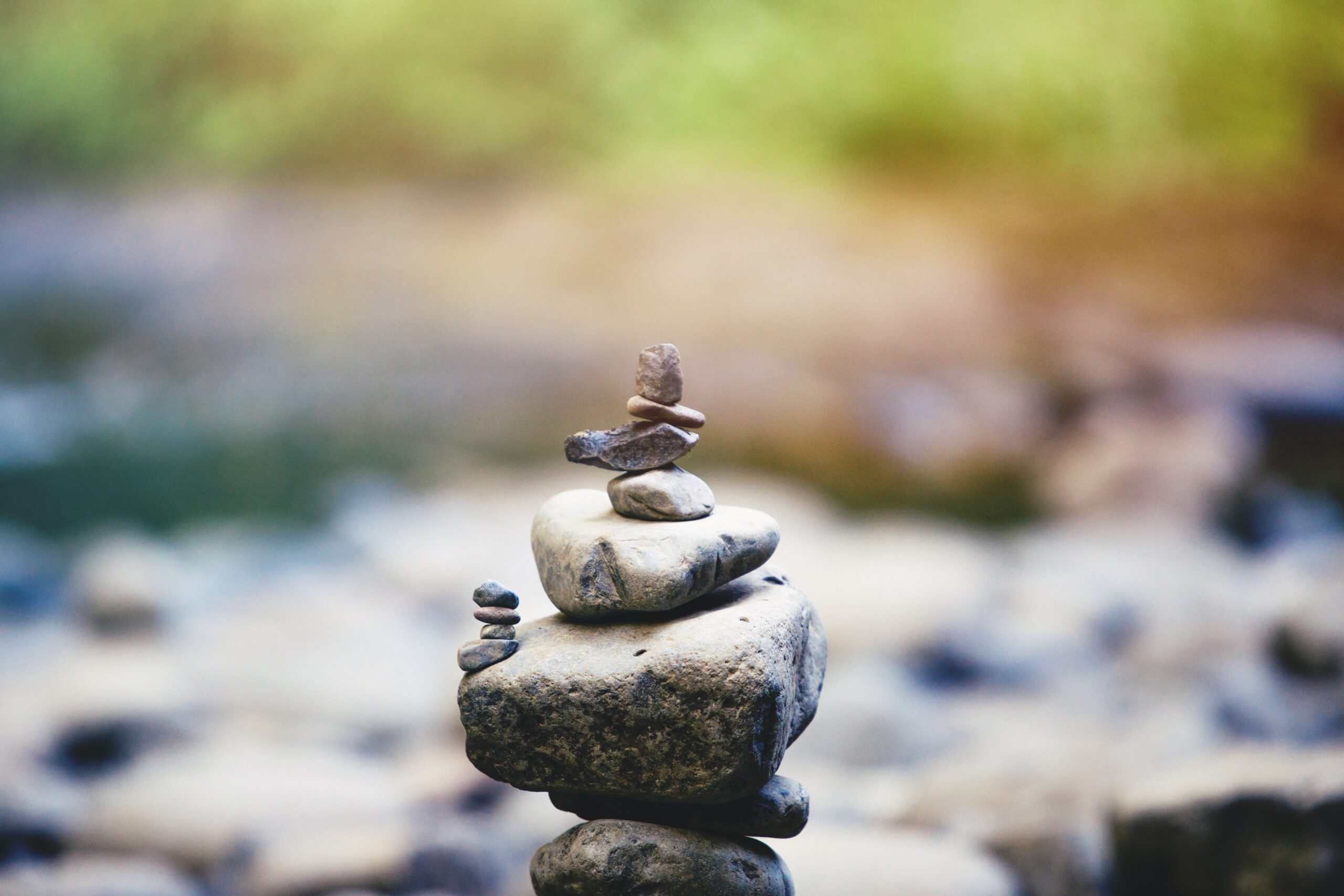 Stack of smooth, balanced stones on a rock surface near water