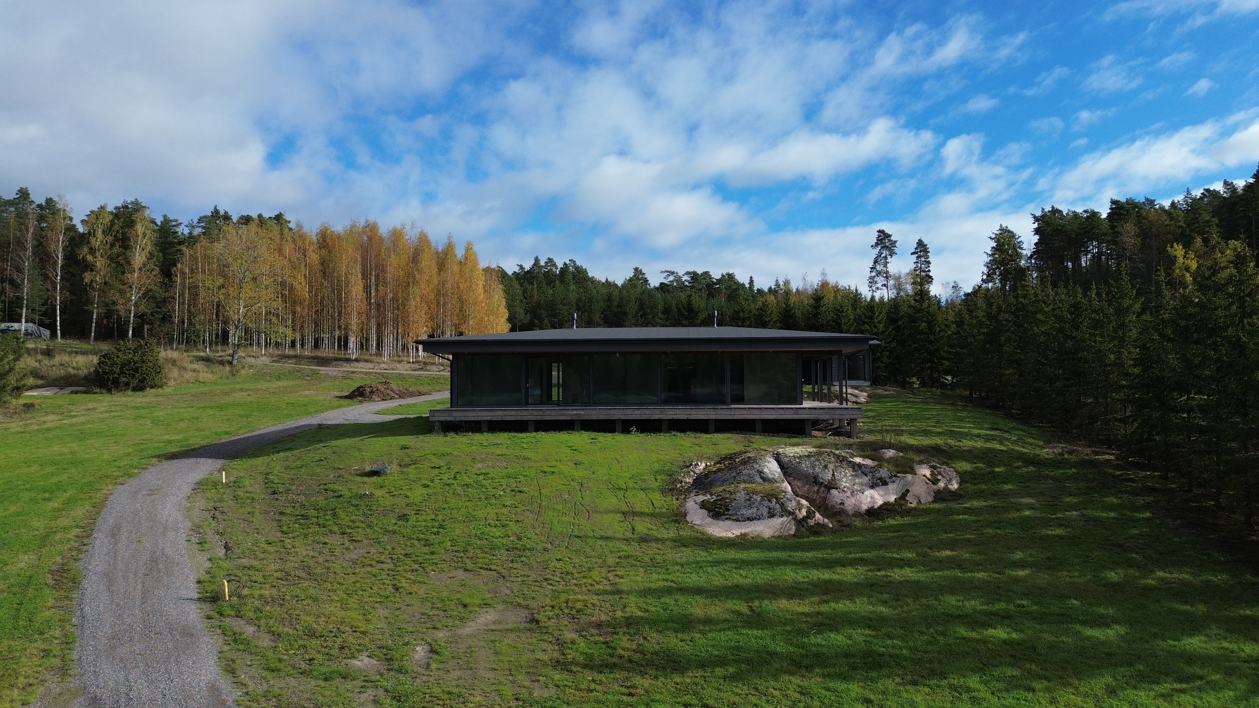 A house with large windows on a lawn and a rock in front.