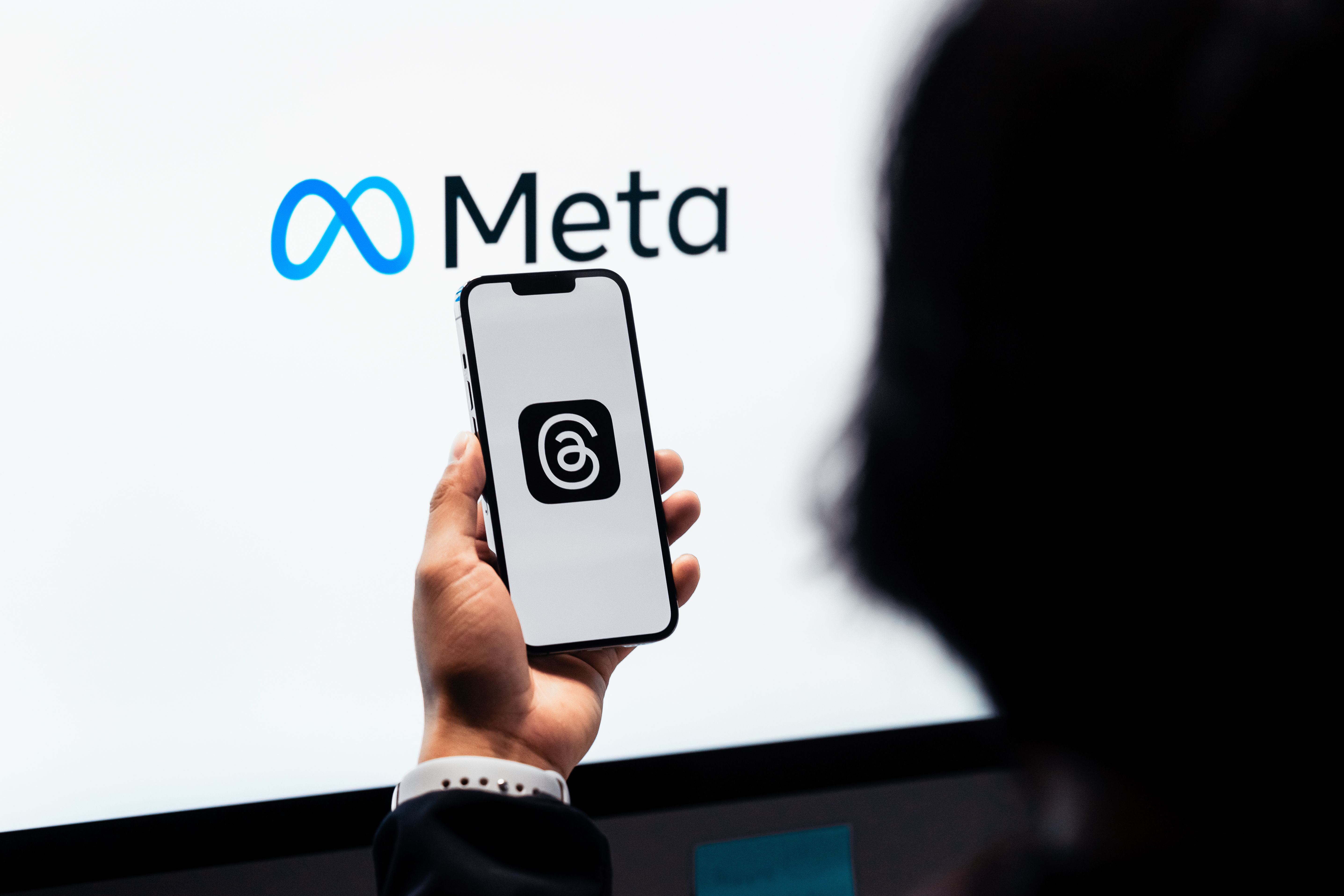 Frau hält Handy in der Hand. Logo von Meta
