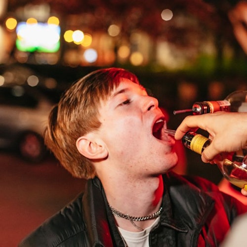 A guy taking a vodka shot straight out of the bottle
