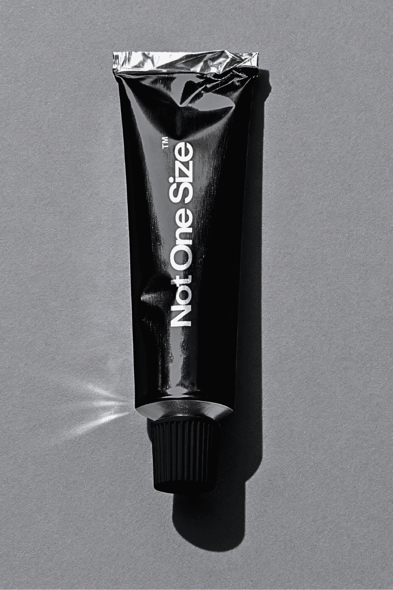 Close-up portrait of a person wearing a gray insulated hooded jacket with the hood up, showing their face framed by the hood against a light background.