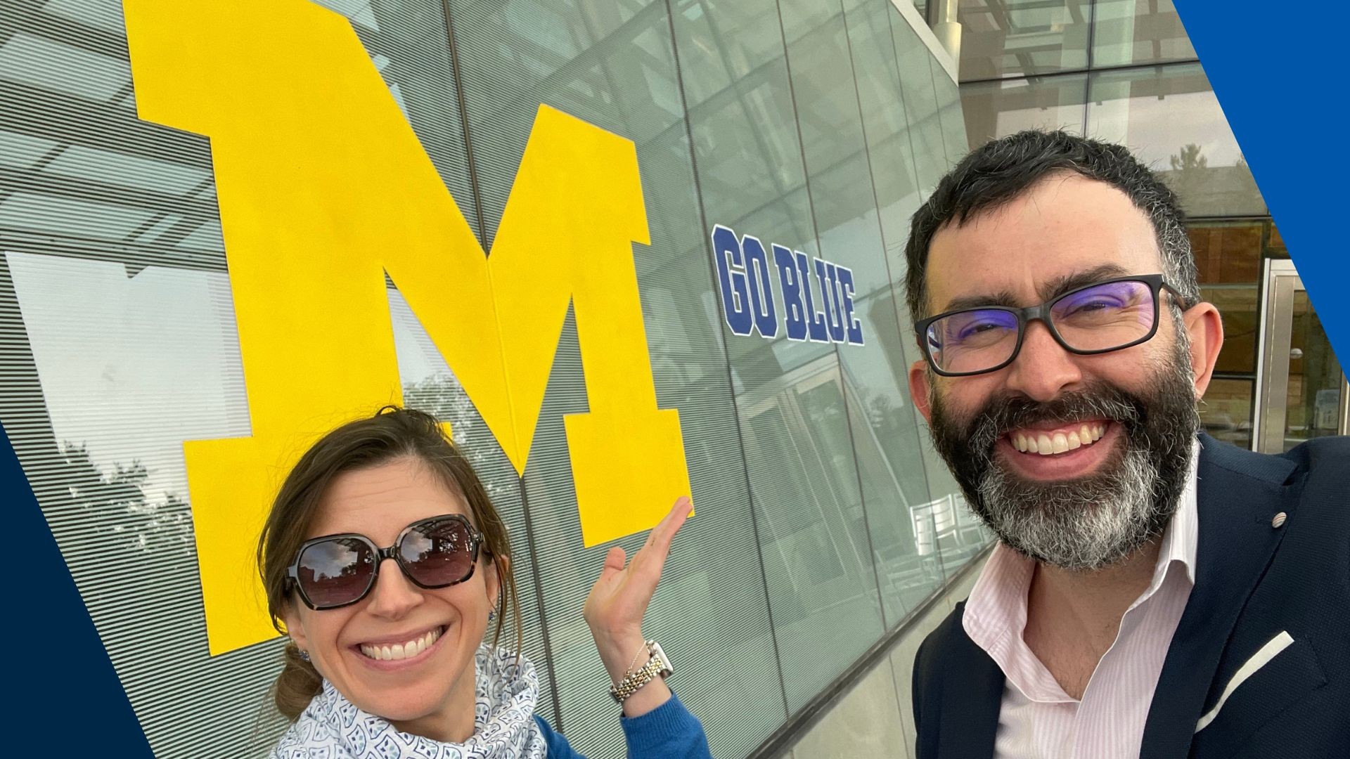 Two smiling individuals pose in front of a large yellow "M" sign, showing their enthusiasm.